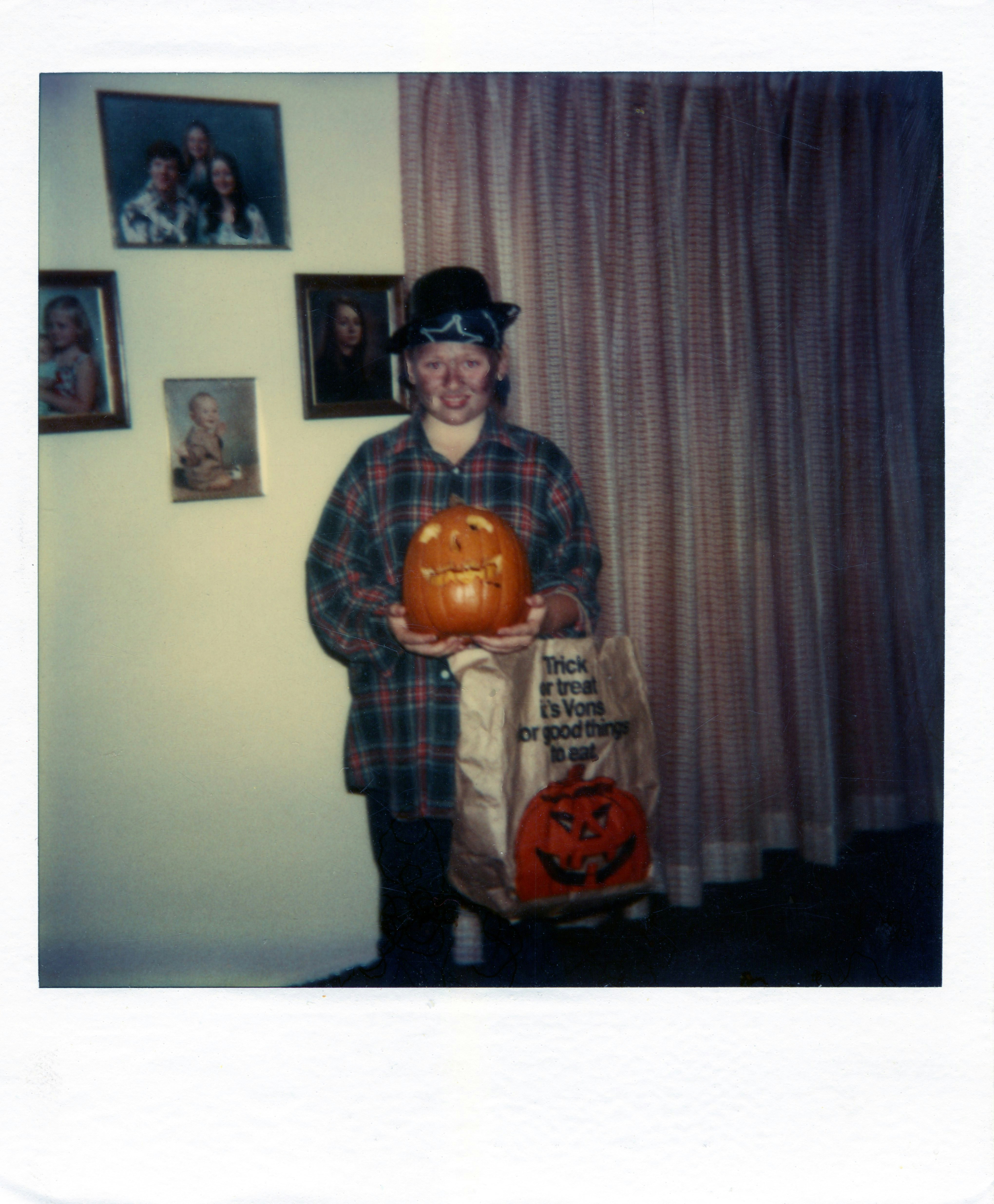 Child in costume holds carved pumpkin and trick-or-treat bag.
