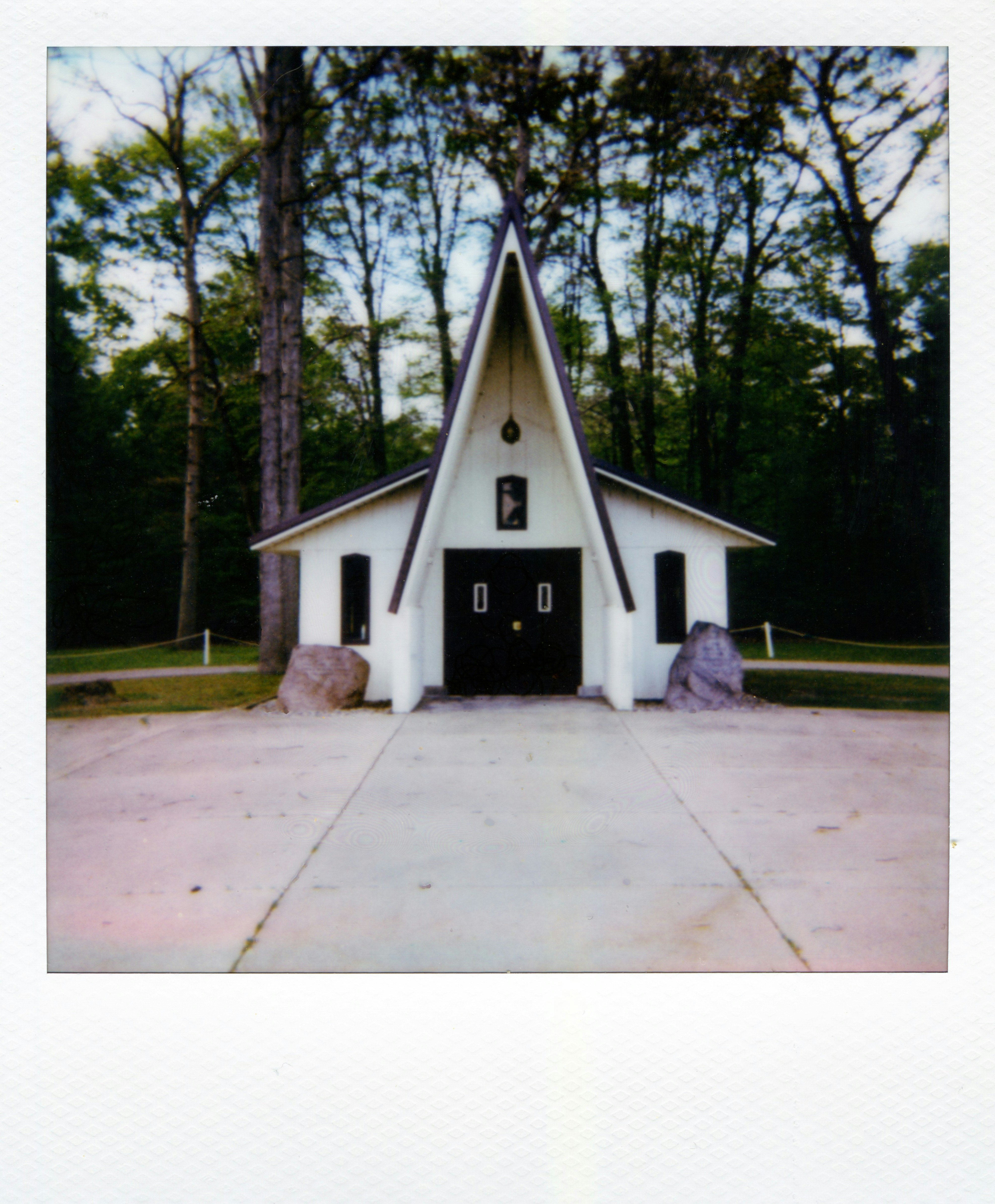 Small white chapel with a pointed roof in forest