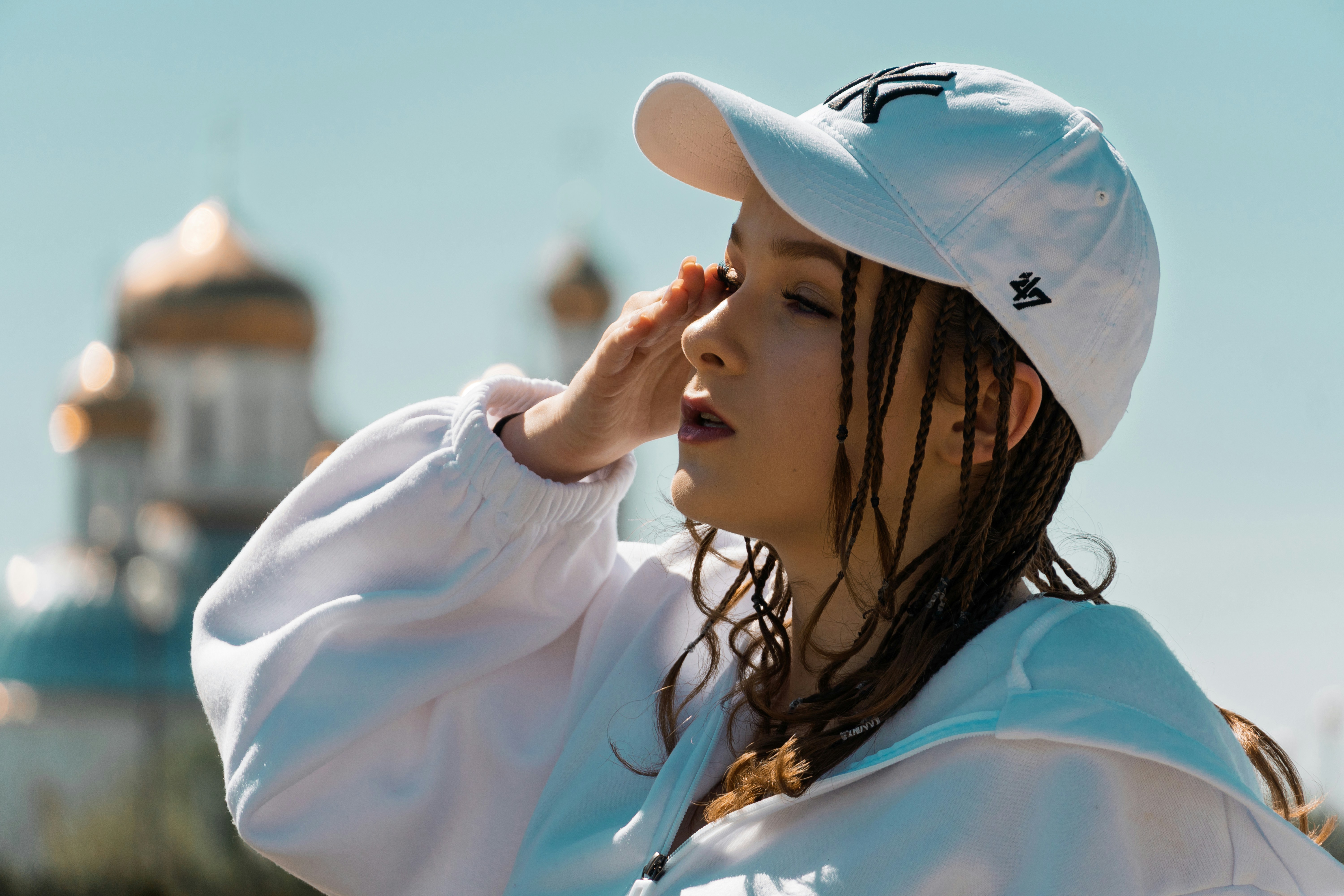 Young woman shielding eyes from sun near golden domes.