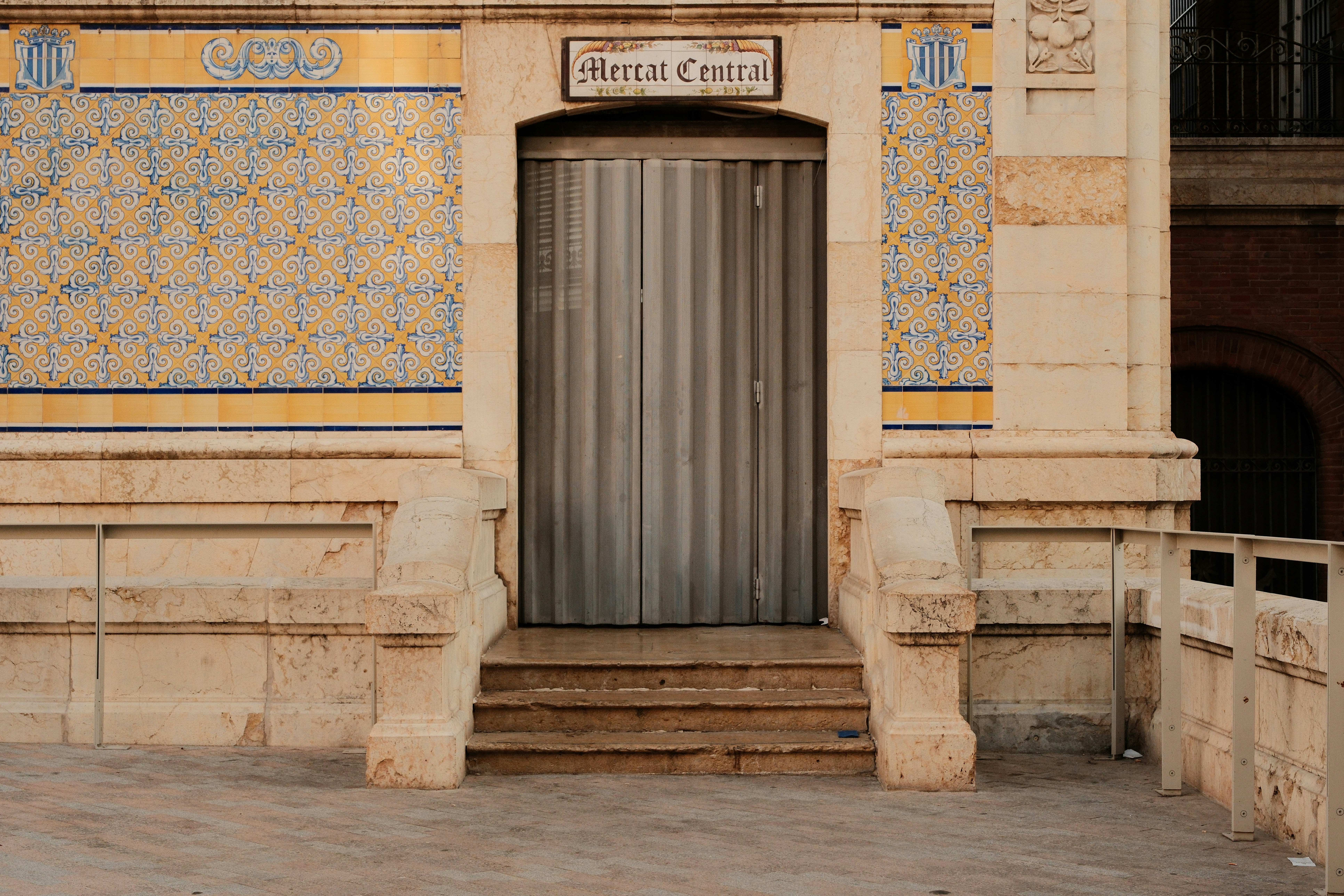 Ornate building entrance with tiled walls and metal door.