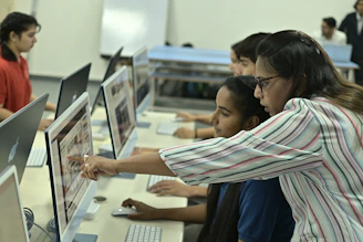 Teacher guiding students on computer in classroom.