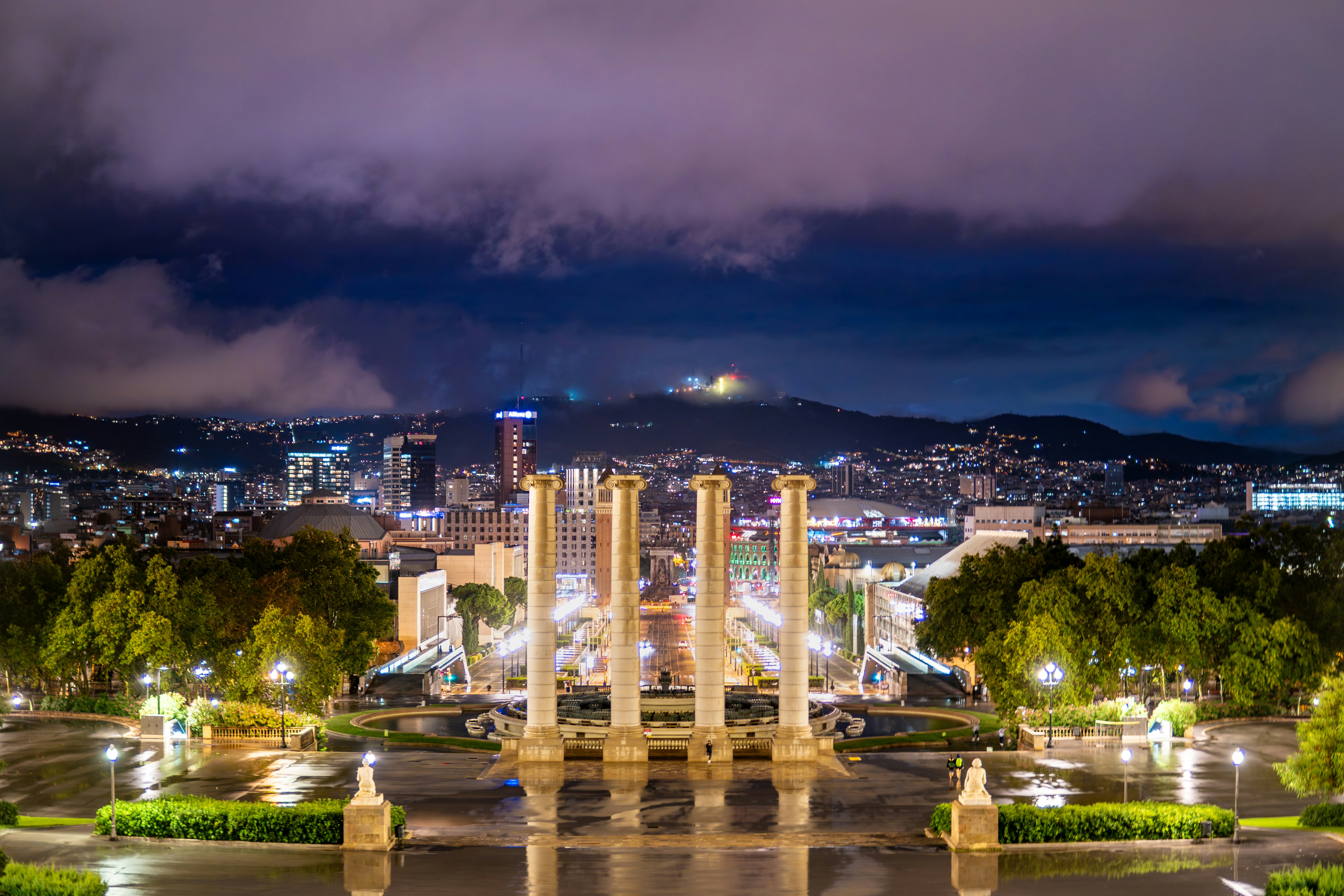 Barcelona's magic fountain at night with city lights and mounta…