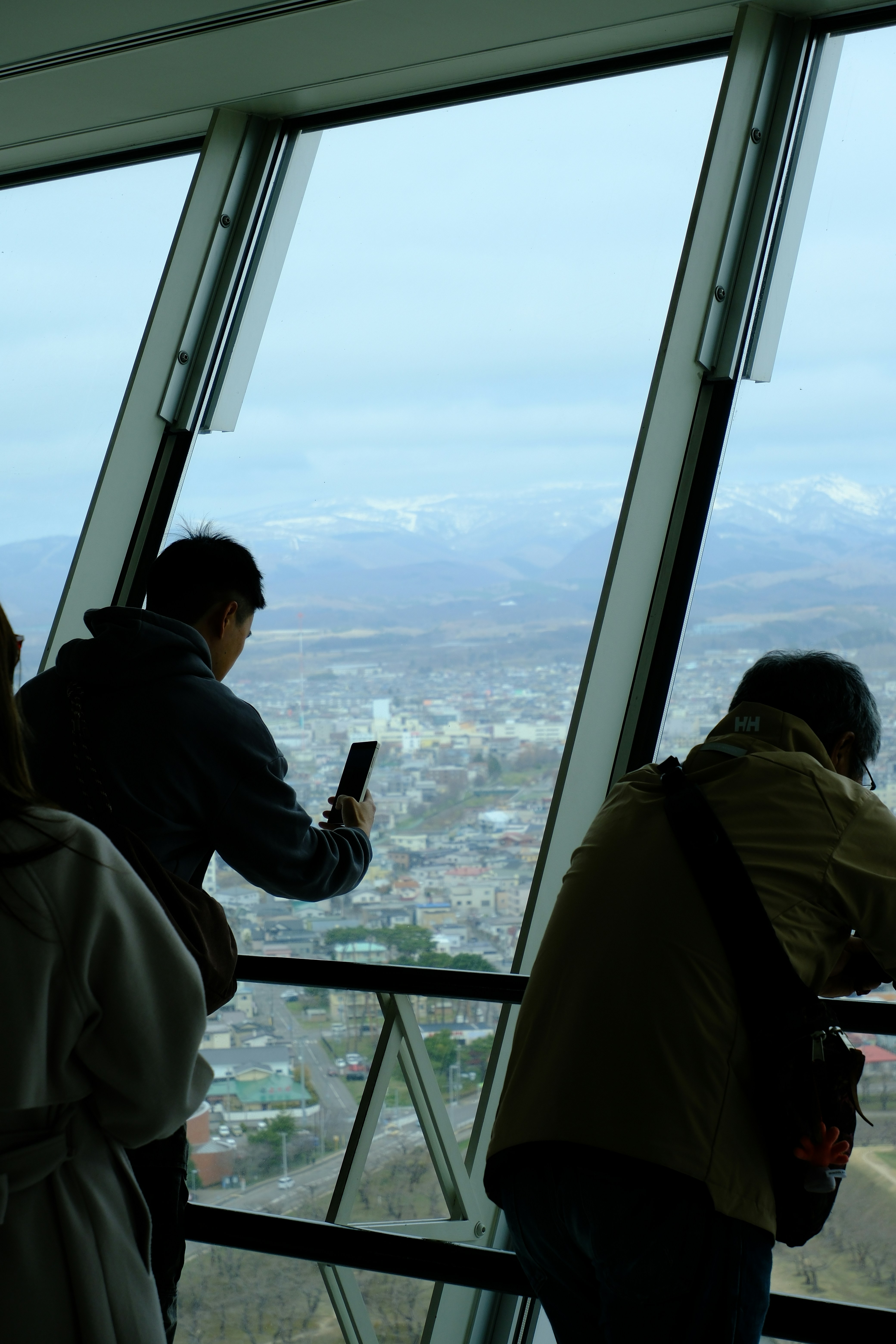 People looking out large window at city and mountains