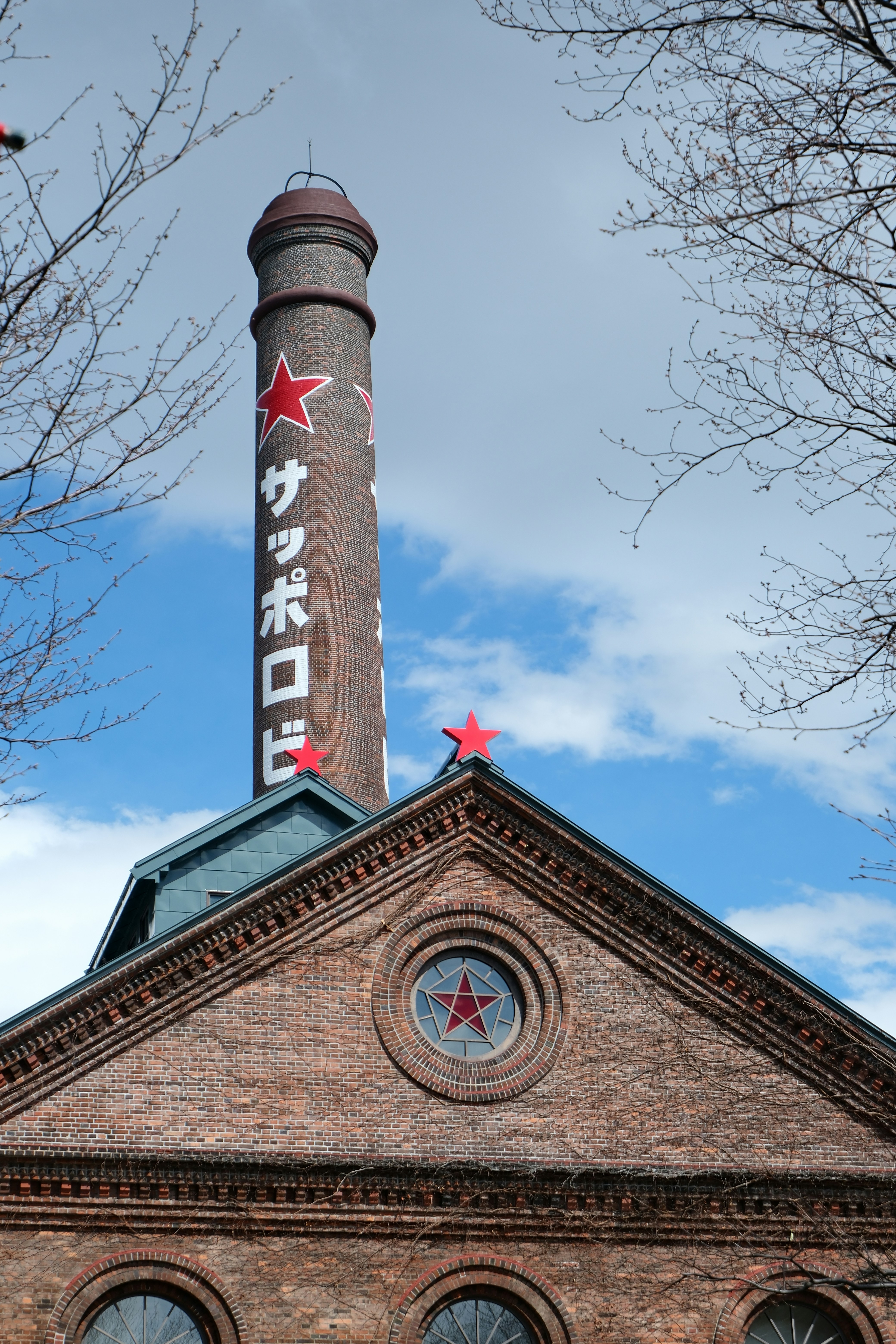 Brick building with a tall chimney and red stars.