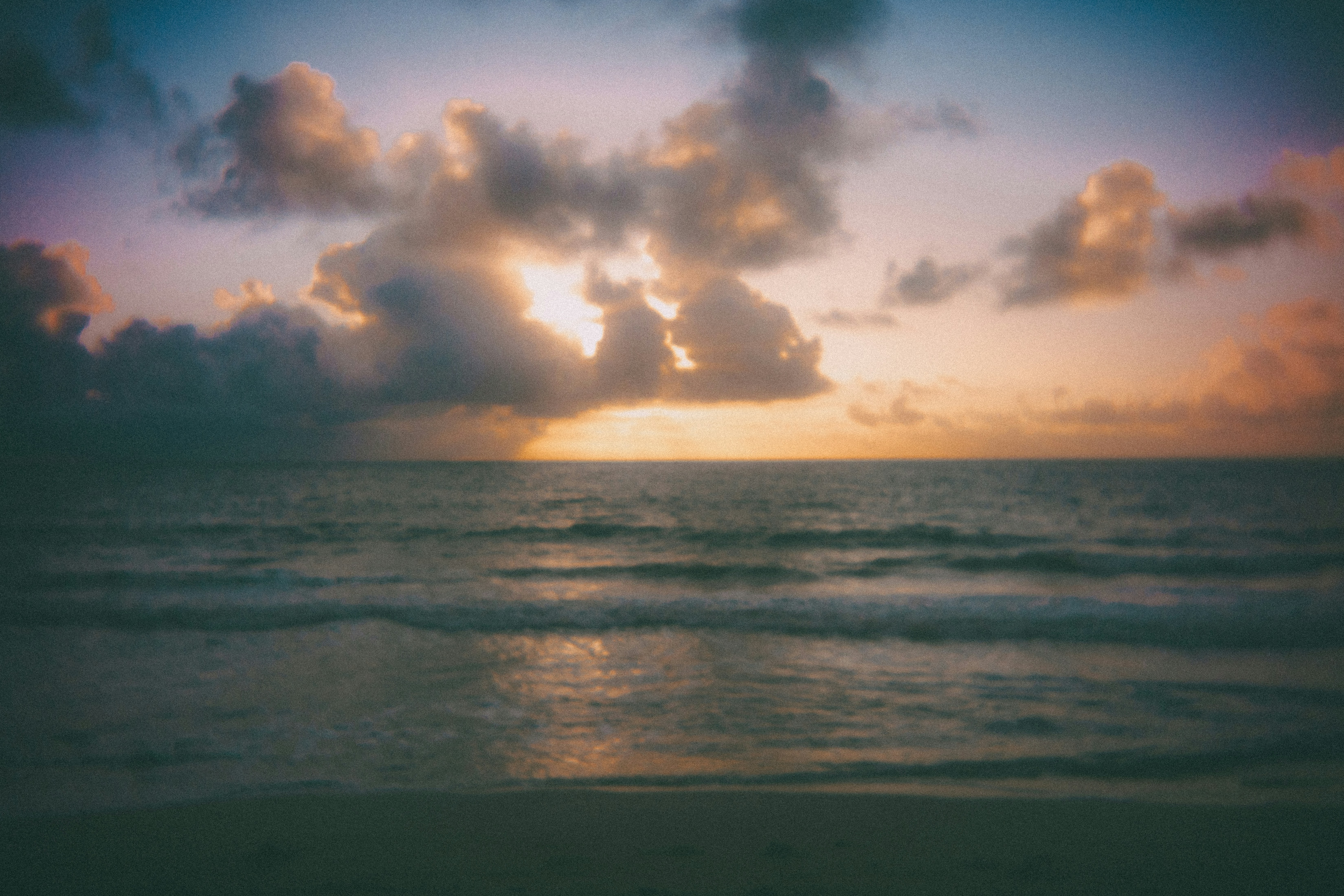Sunrise over a calm ocean with dramatic clouds