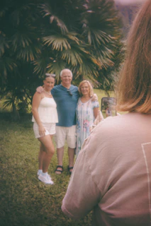 Three people posing for a photo outdoors with palm trees