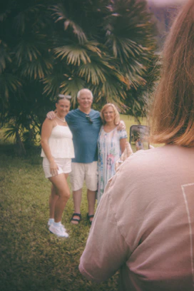Three people posing for a photo outdoors with palm trees