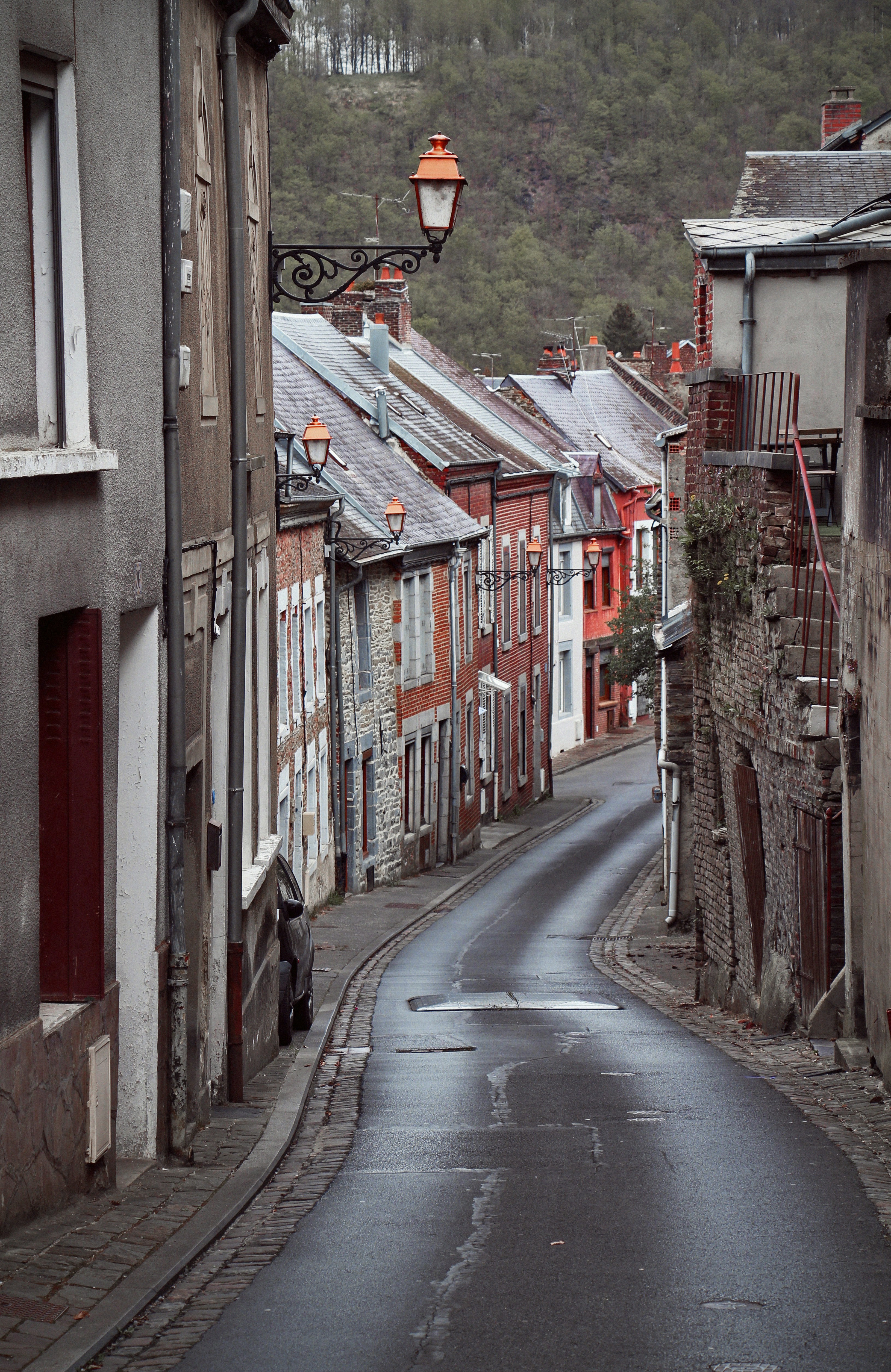 Une rue étroite et humide serpente à travers d’anciens bâtiments européens.