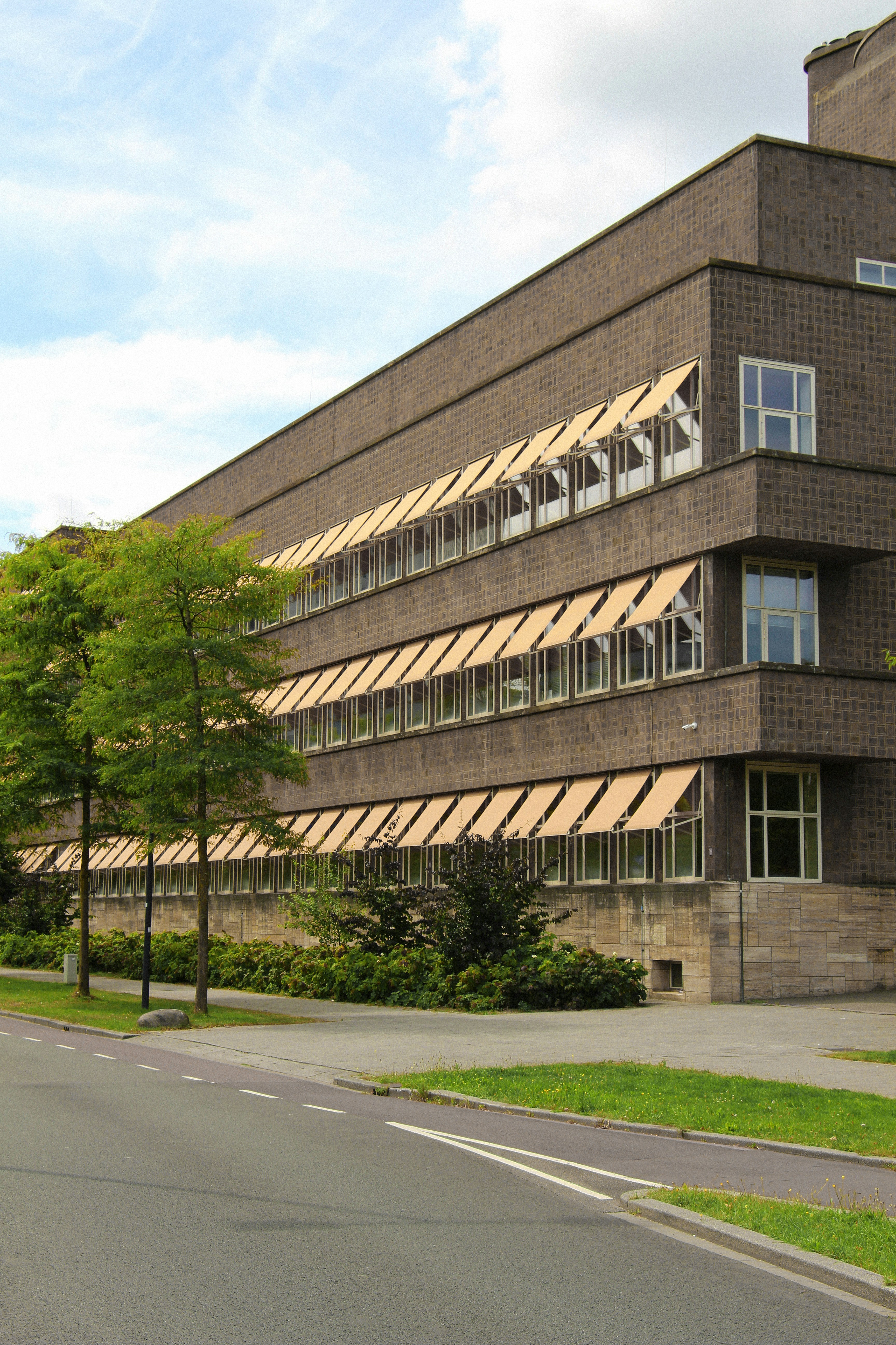 Bâtiment moderne avec plusieurs étages, fenêtres et auvents.