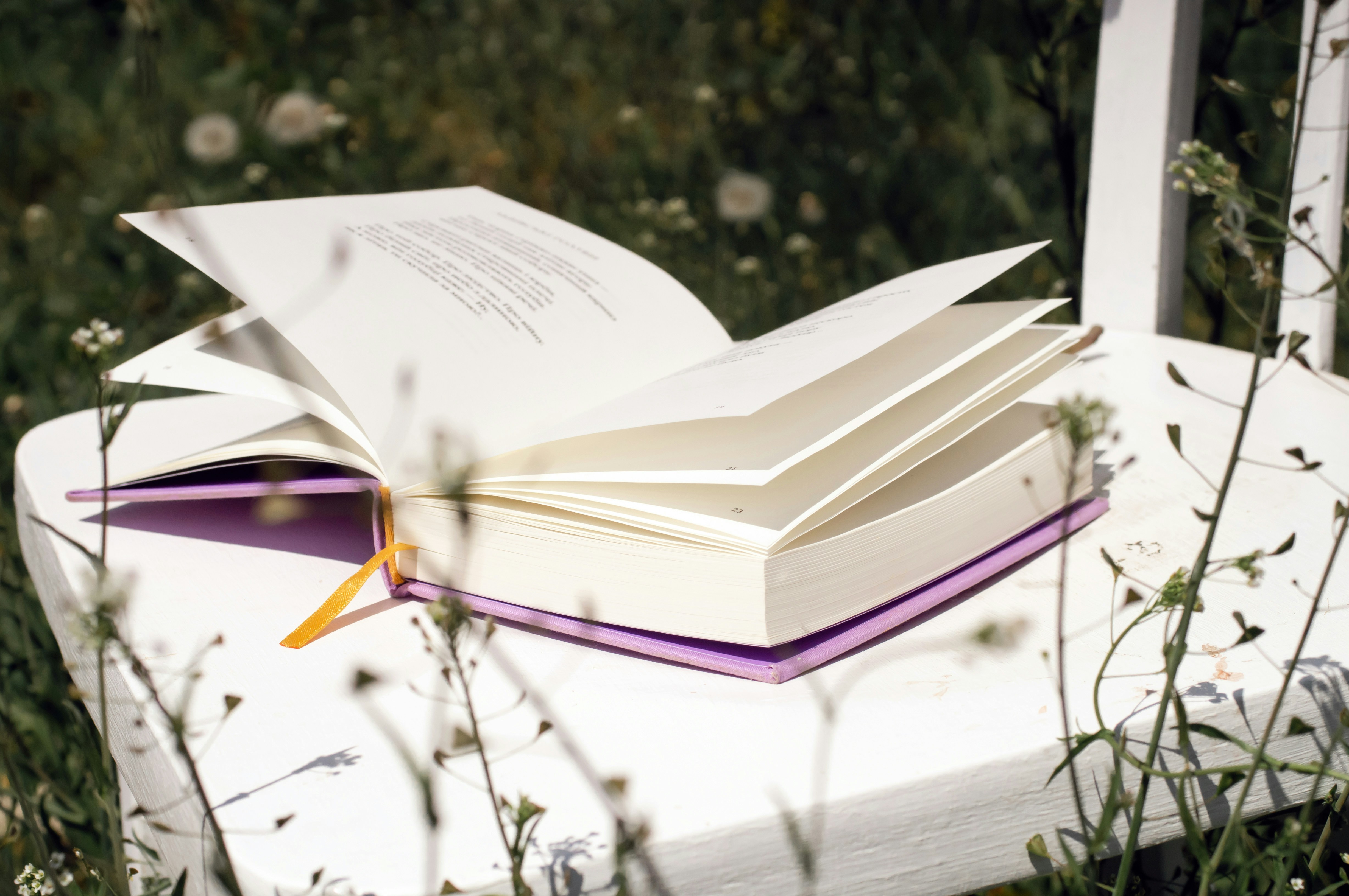 Open book resting on a white chair outdoors