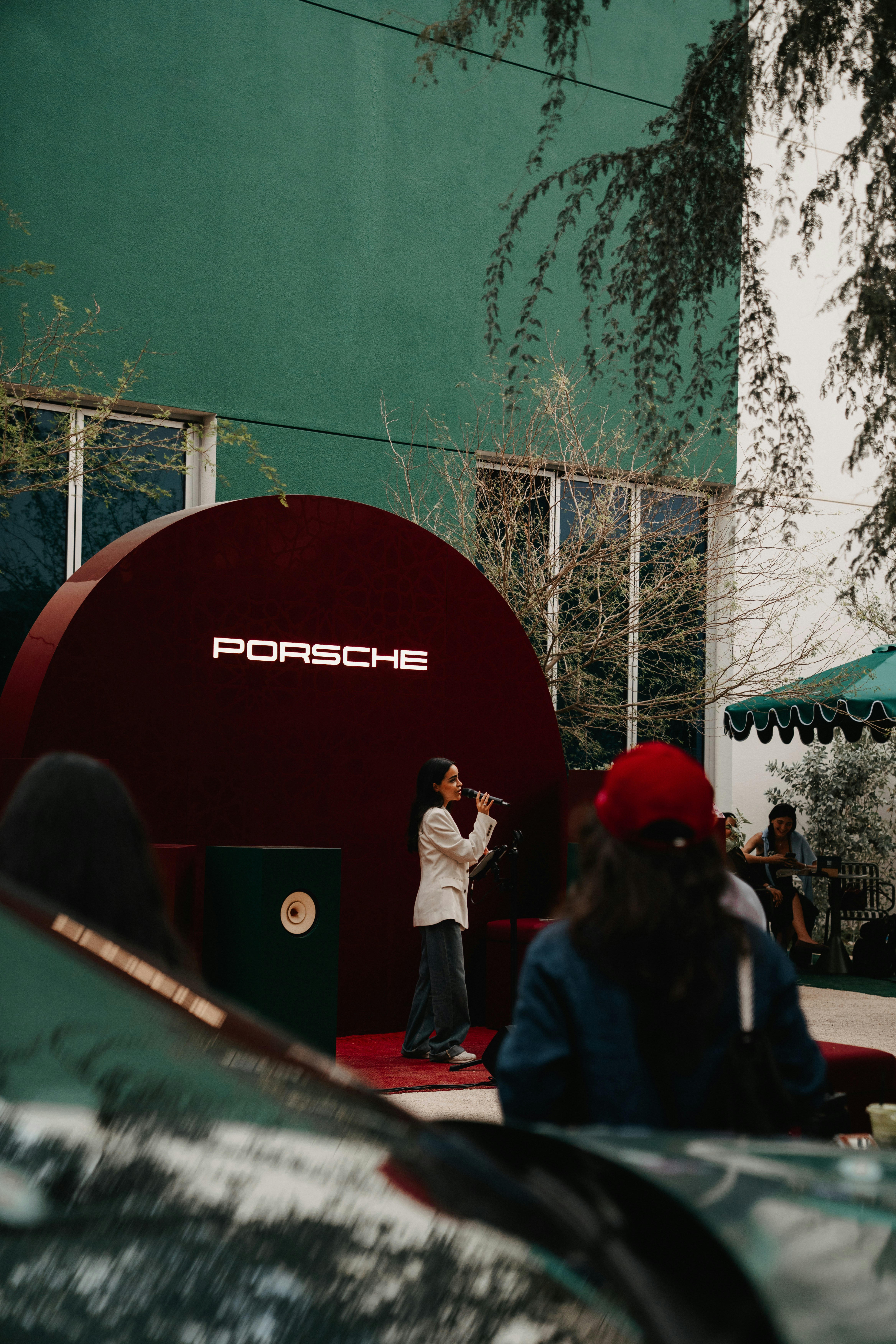 A woman sings on a stage with a porsche logo