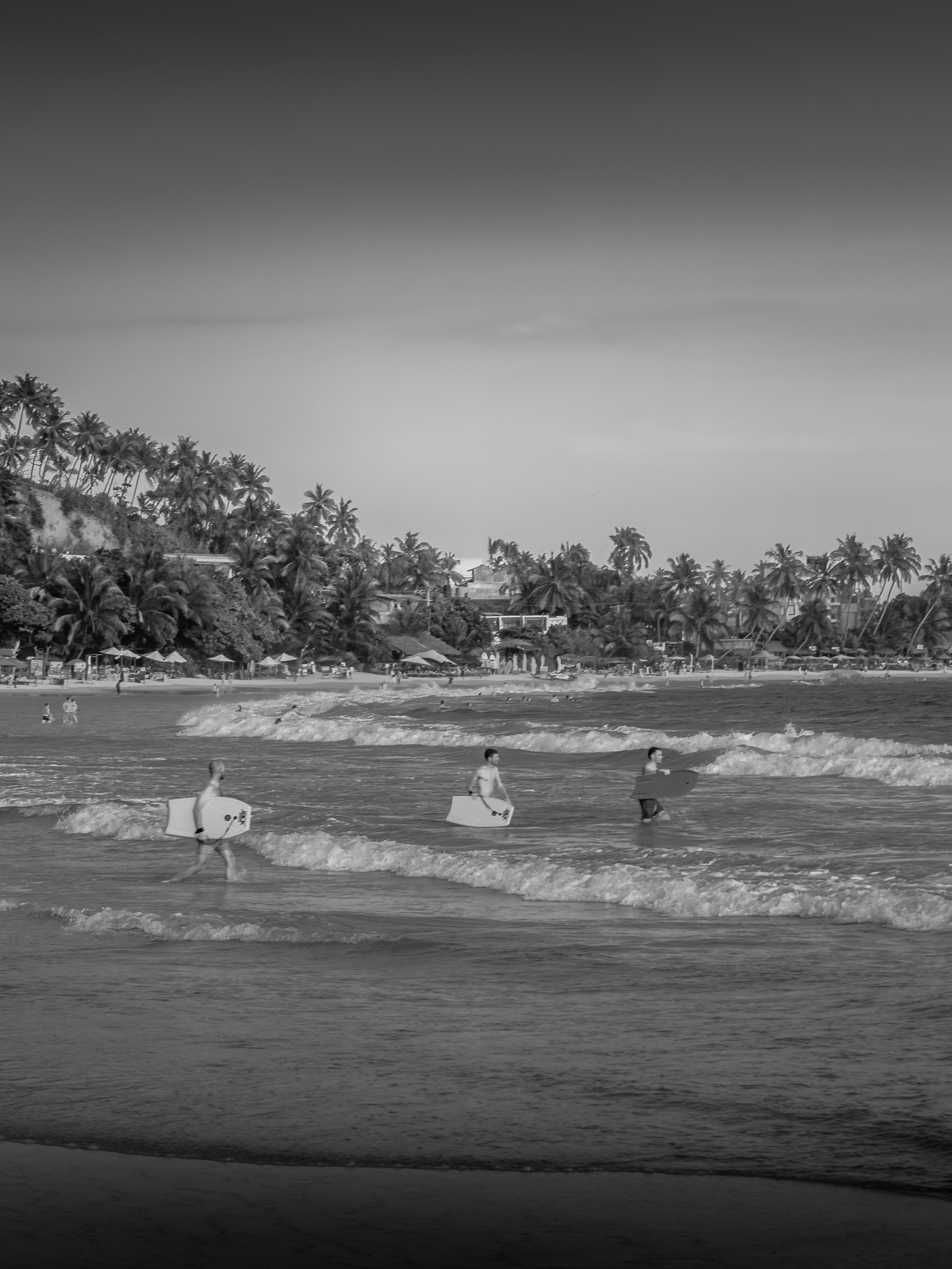 People with surfboards wading into the ocean waves