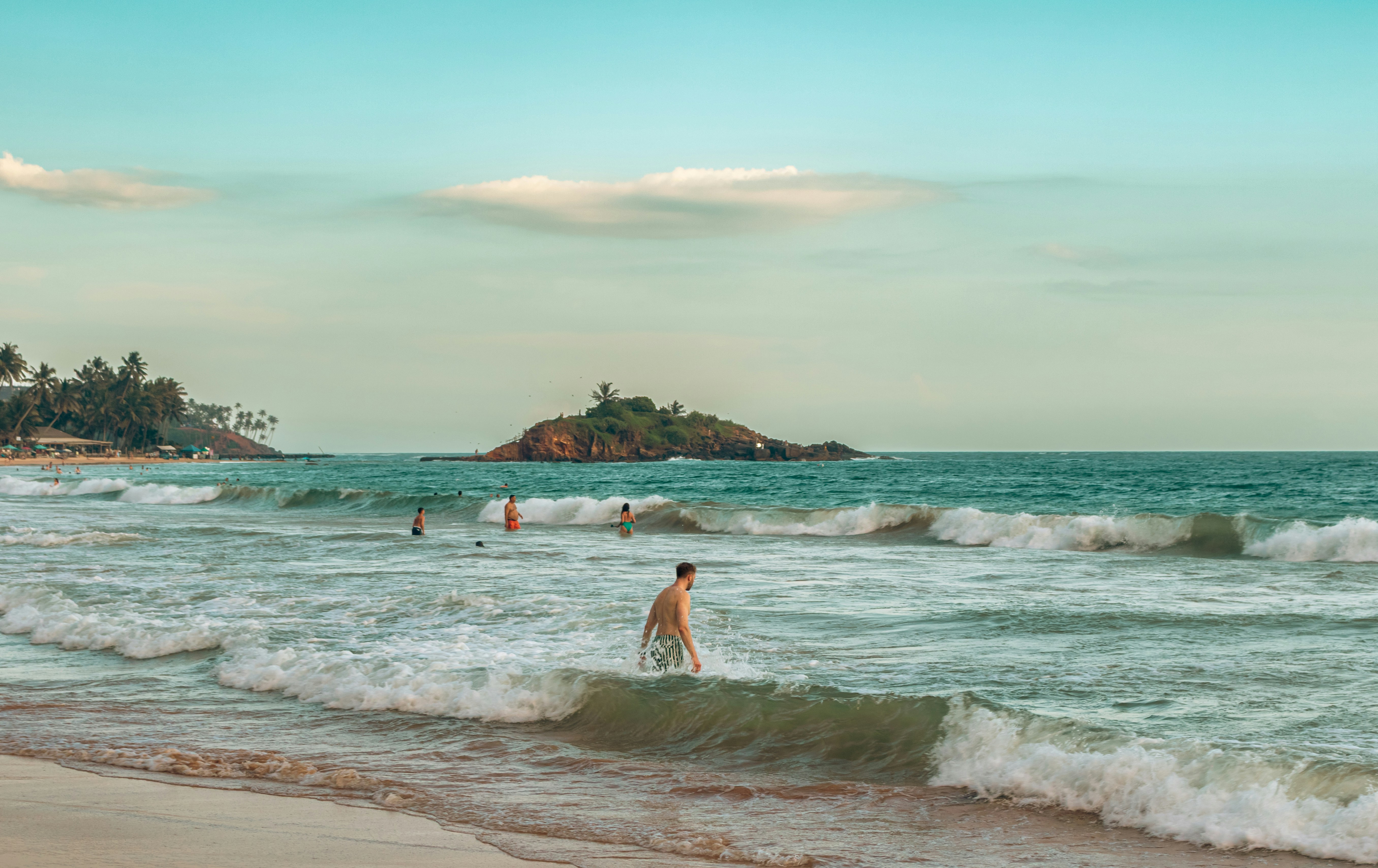 Man wading into the ocean with small island background.