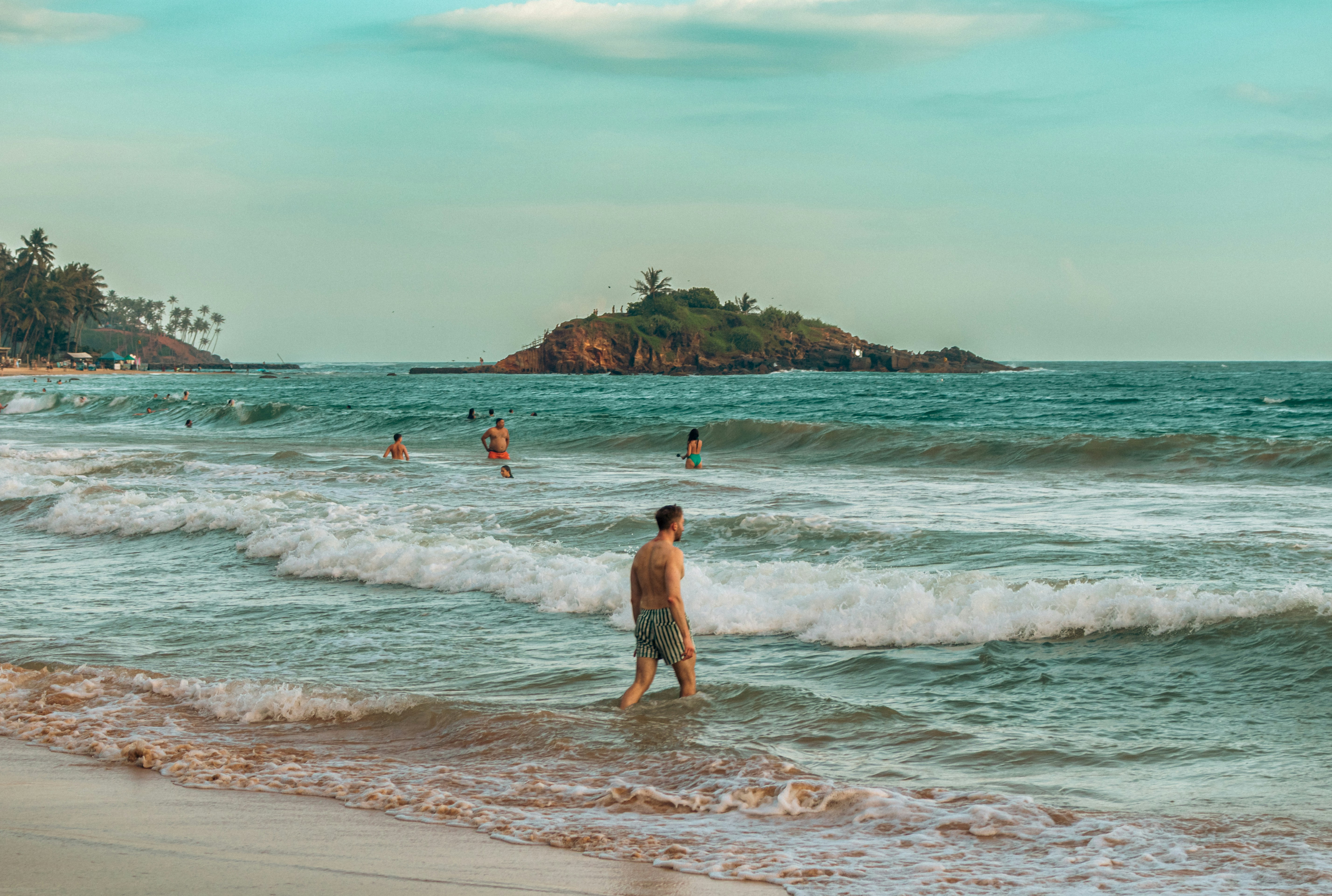 People swim in the ocean near a tropical island.