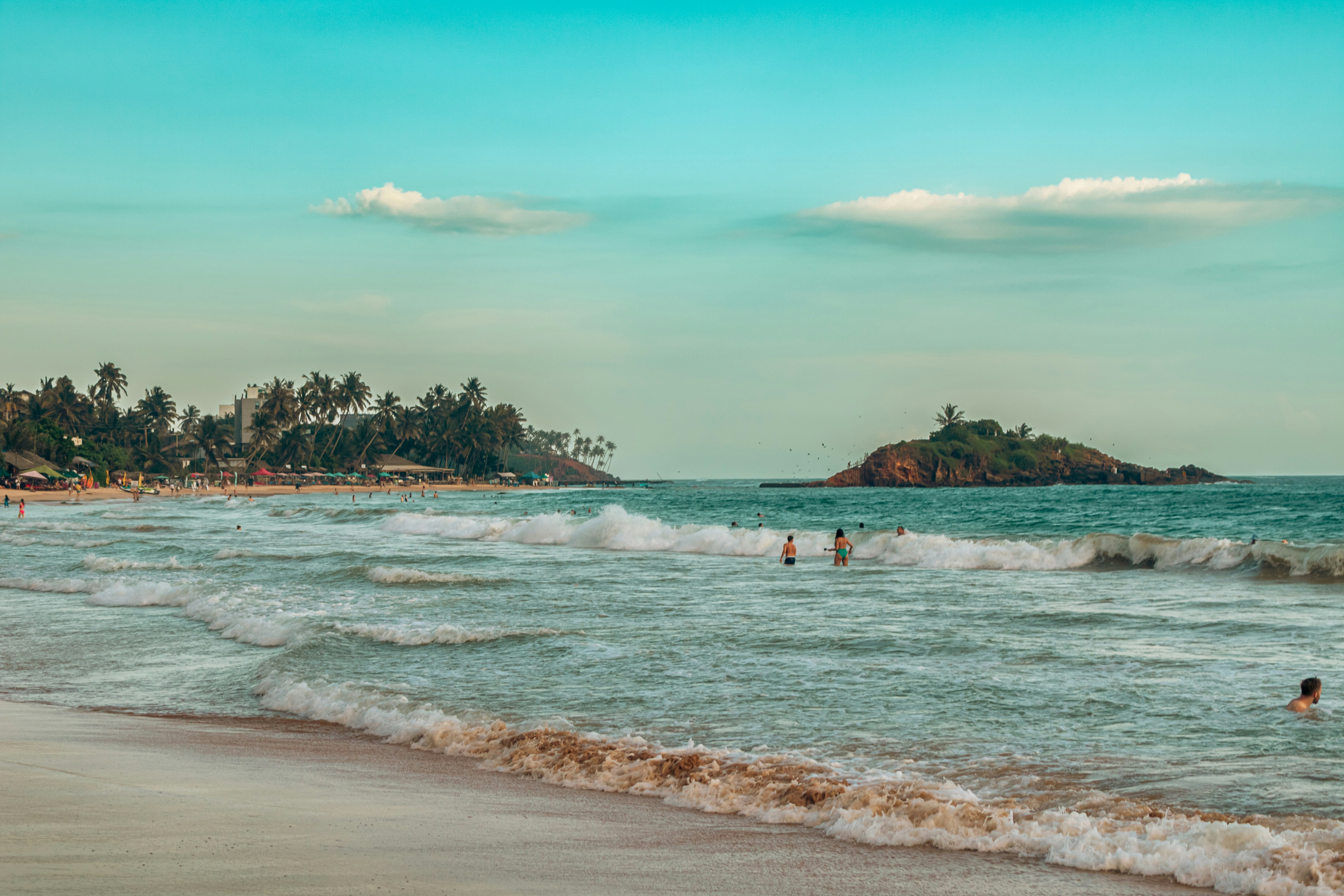 Waves crash on a tropical beach with distant island.