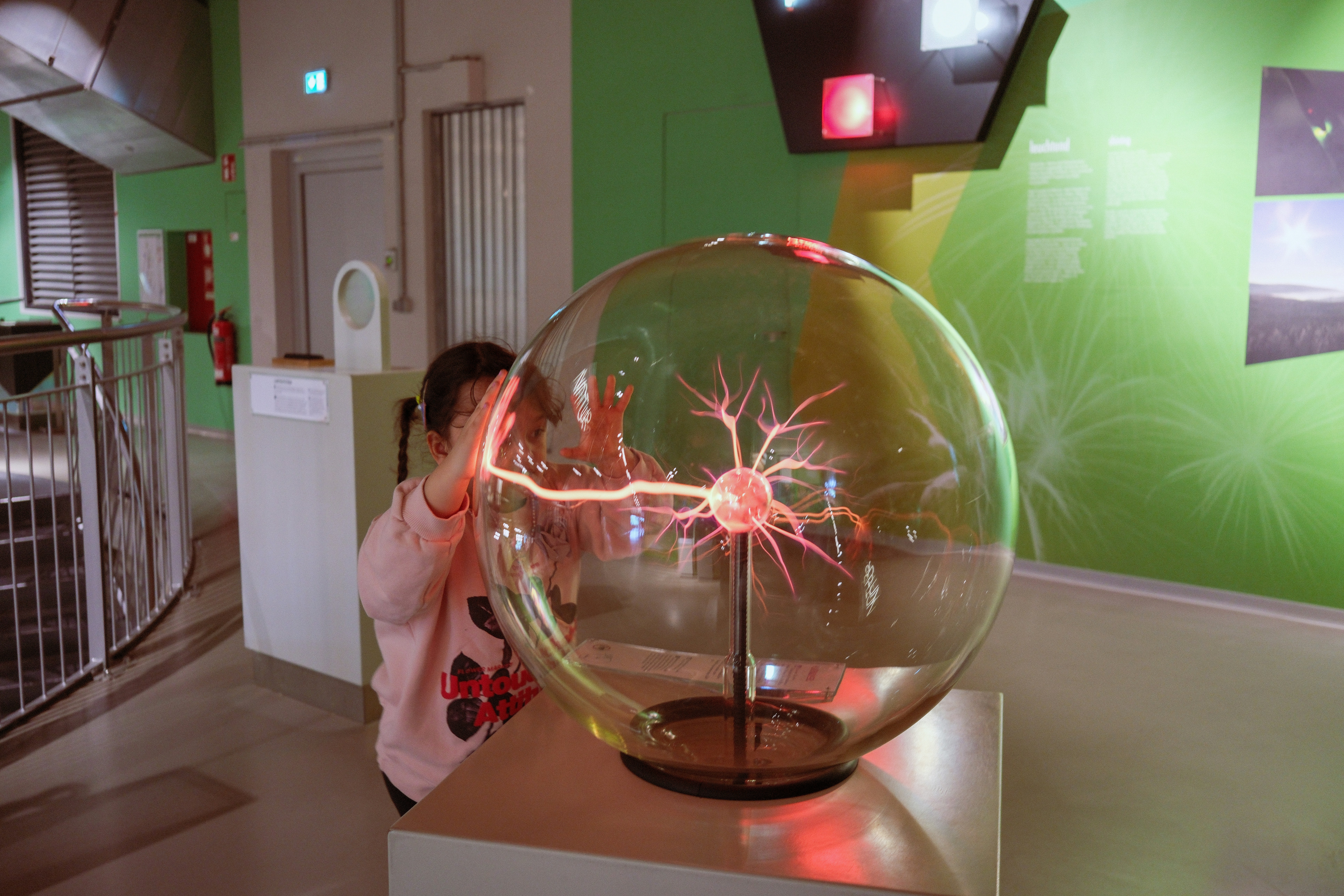 Anak menyentuh bola plasma dalam pameran sains.