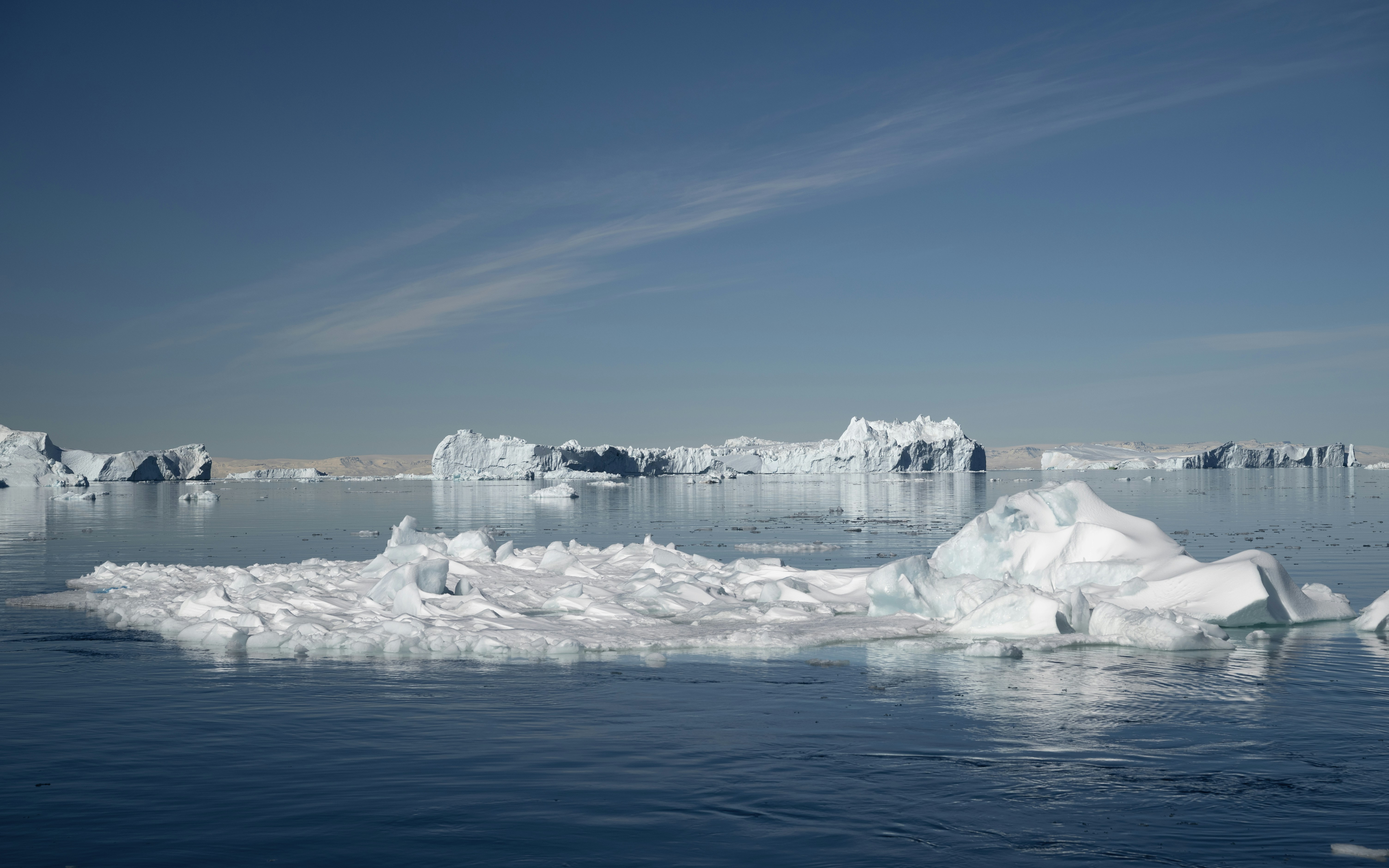 Des icebergs flottant sur un océan calme sous un ciel dégagé