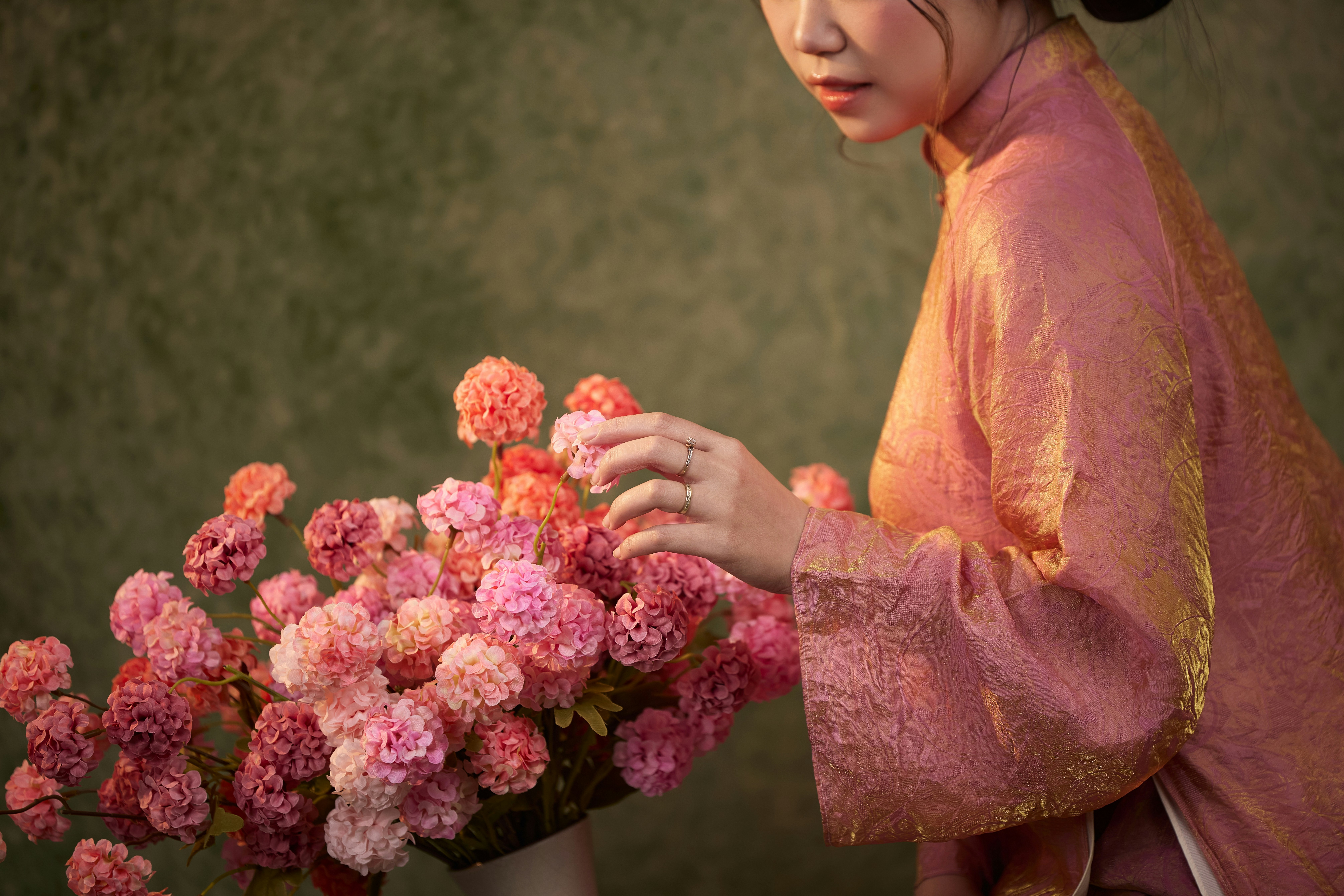 Mujer con traje tradicional arreglando flores rosas