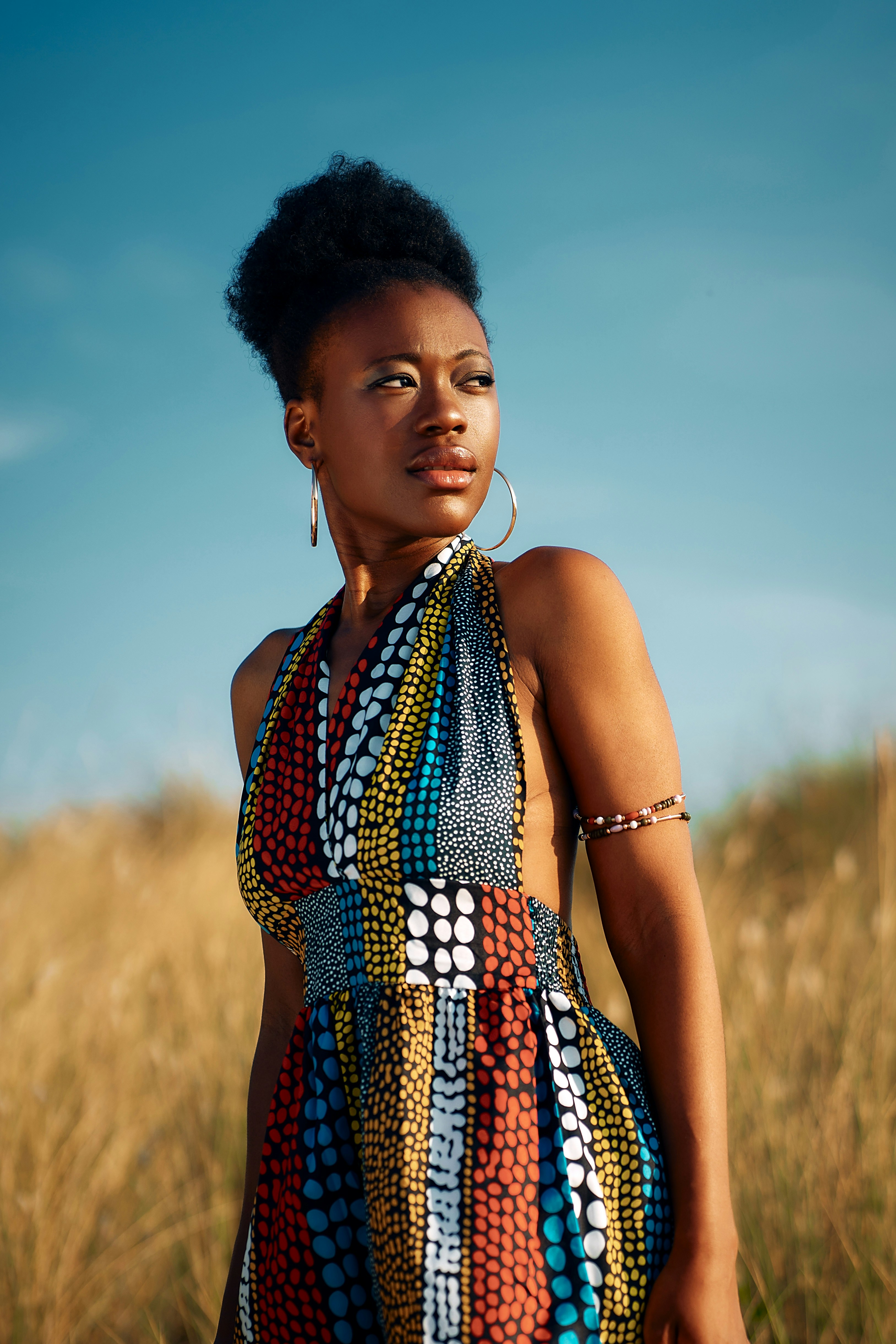 Photo of Young woman in vibrant patterned dress in golden field. by JR Clavant