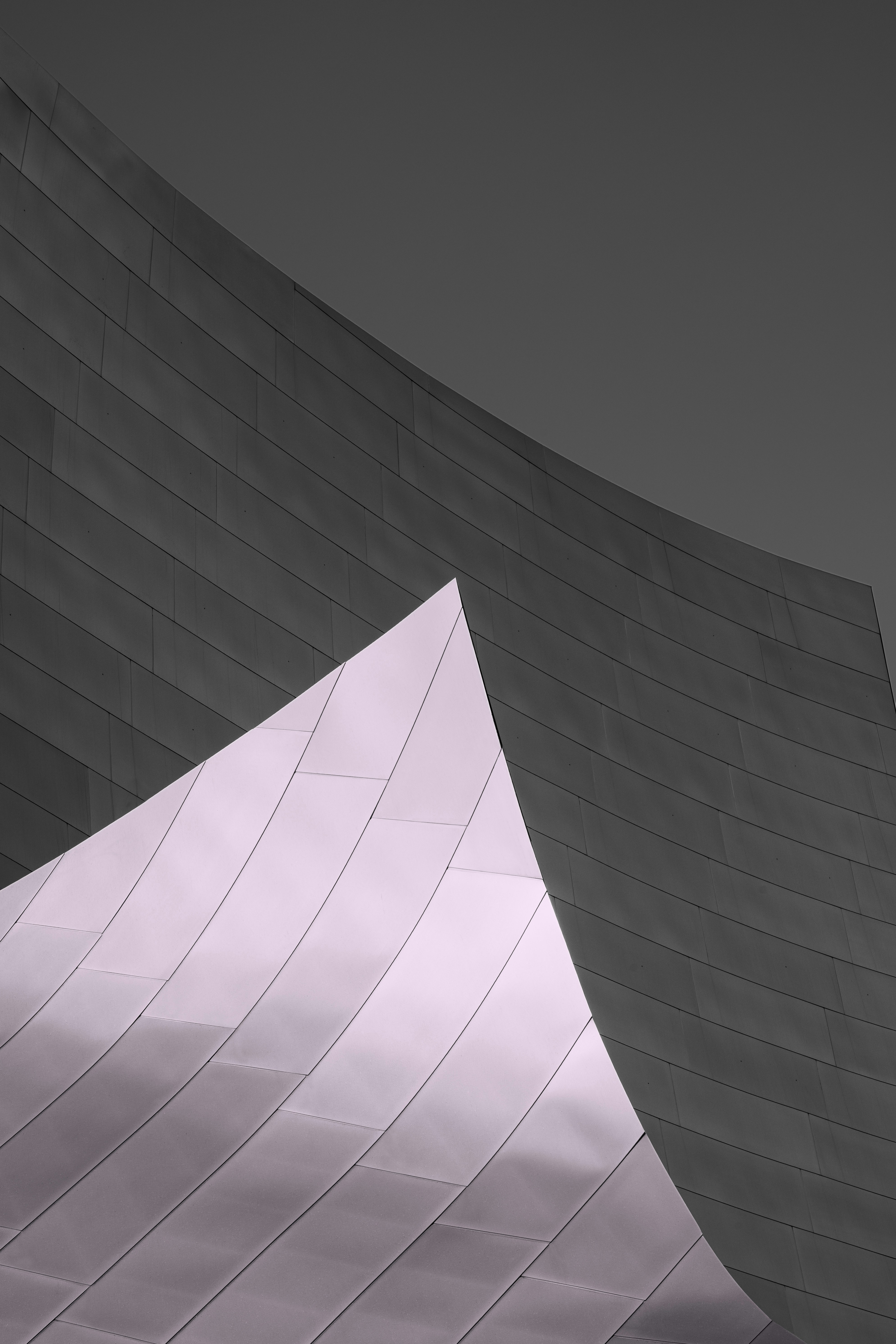 Forme architettoniche metalliche curve contro un cielo grigio
