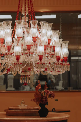 Ornate red and white chandelier above a table with flowers.