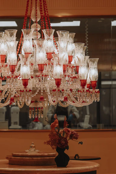 Ornate red and white chandelier above a table with flowers.