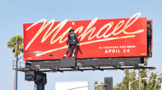 A person on a red billboard advertising "michael" movie.