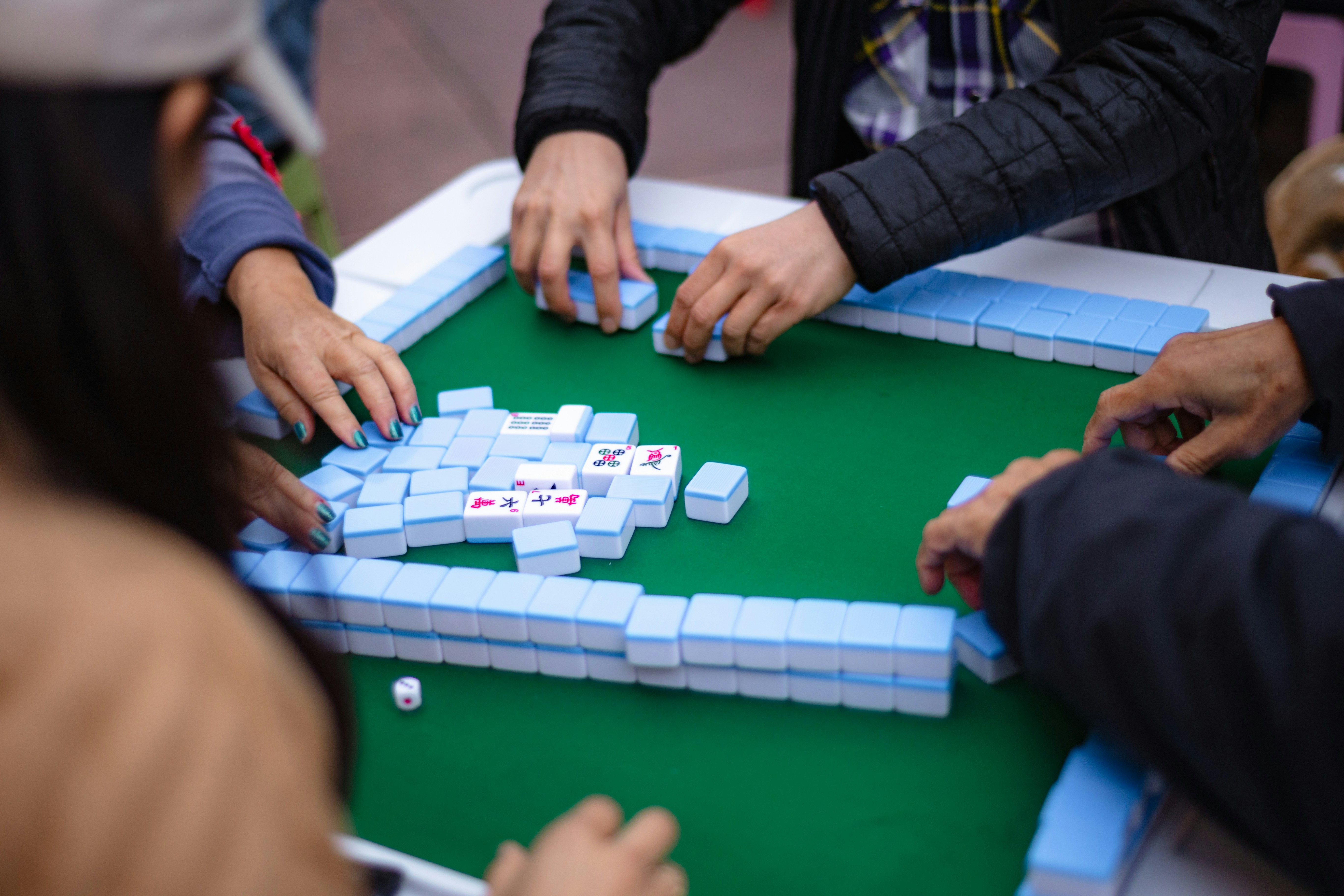People playing mahjong on a green table