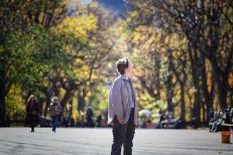 A person stands in a park with colorful autumn trees