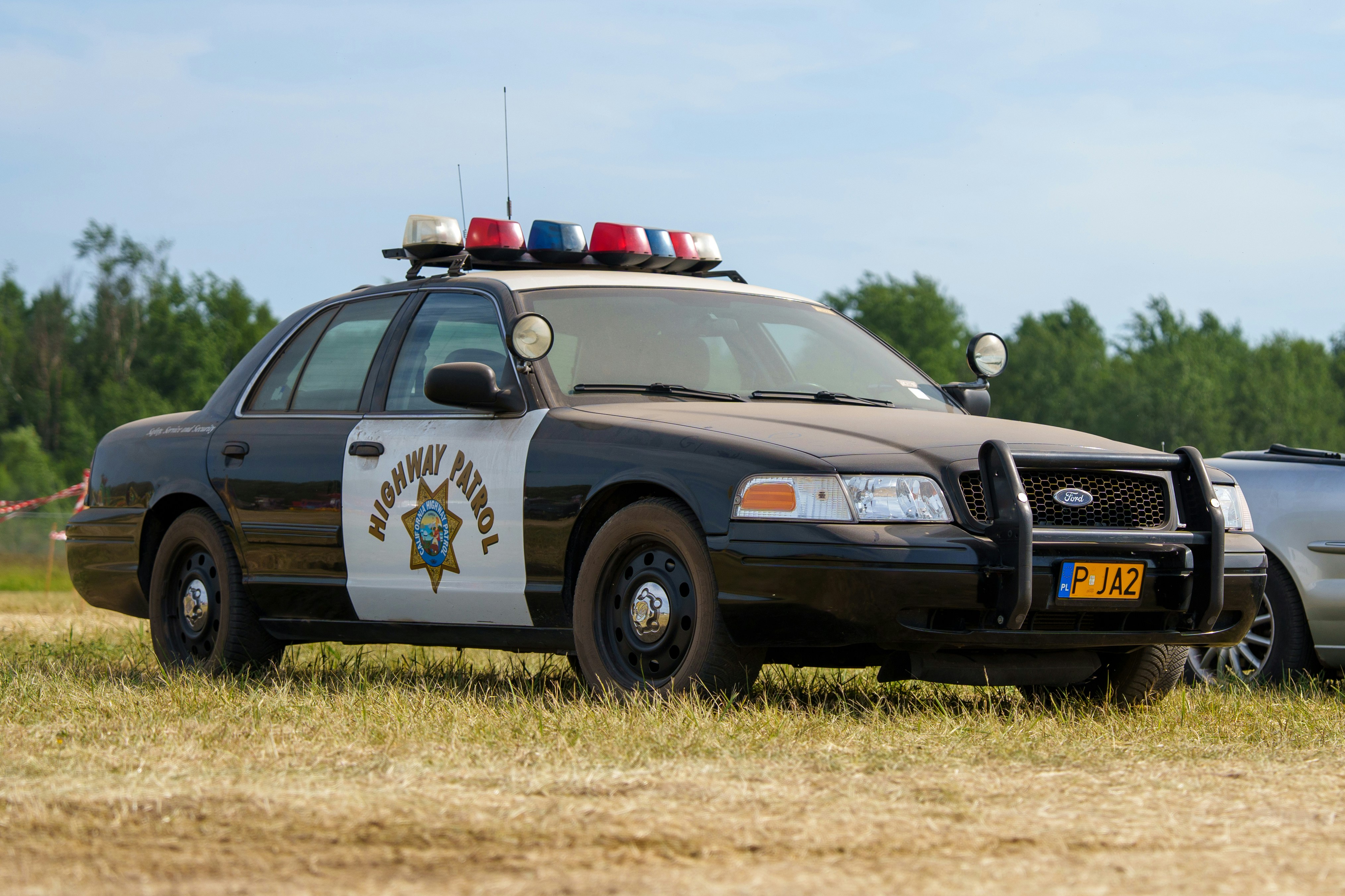 A highway patrol car parked on a grassy field.