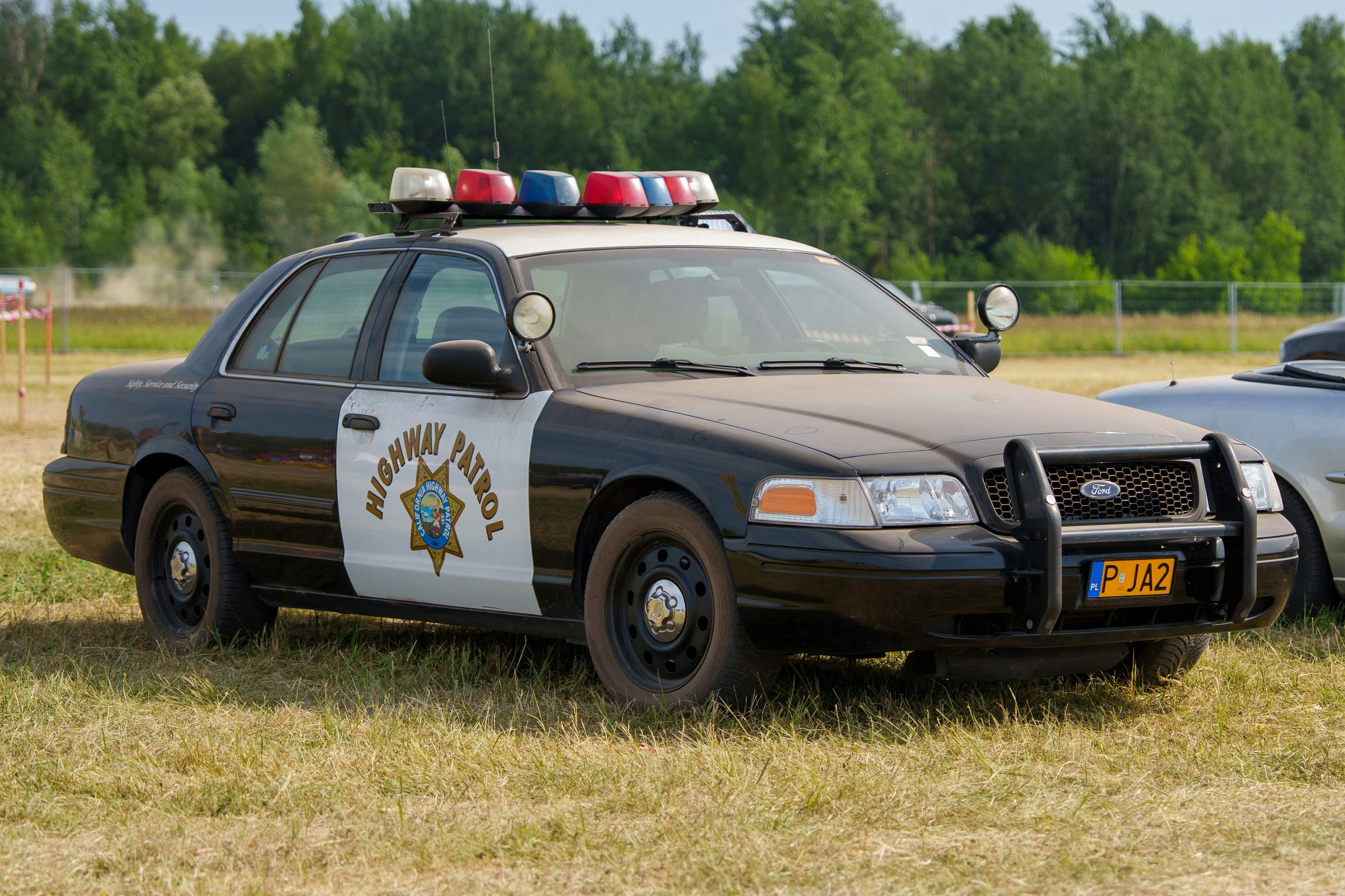 A black and white highway patrol car parked on grass.