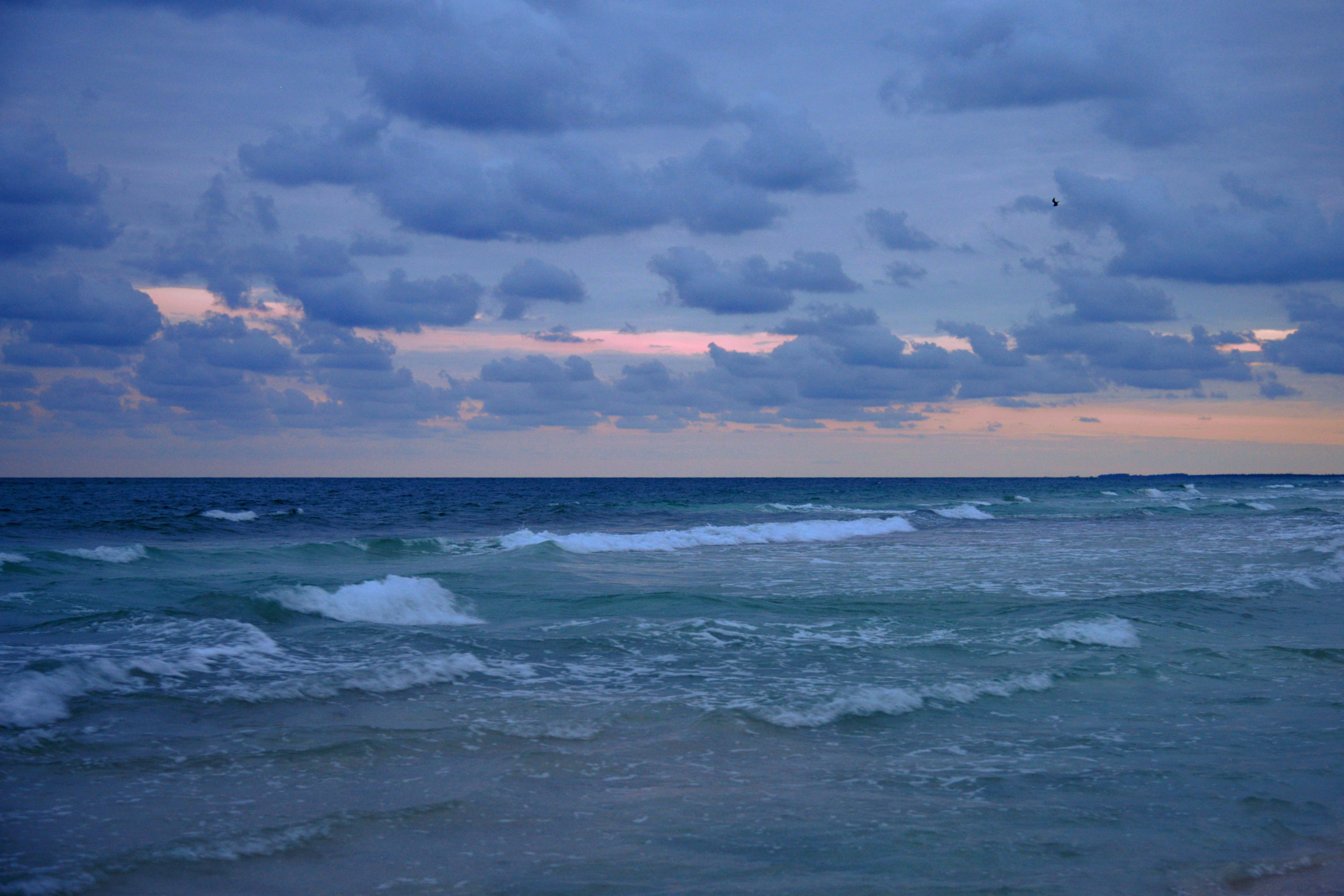 Ocean waves under a cloudy sky at dusk