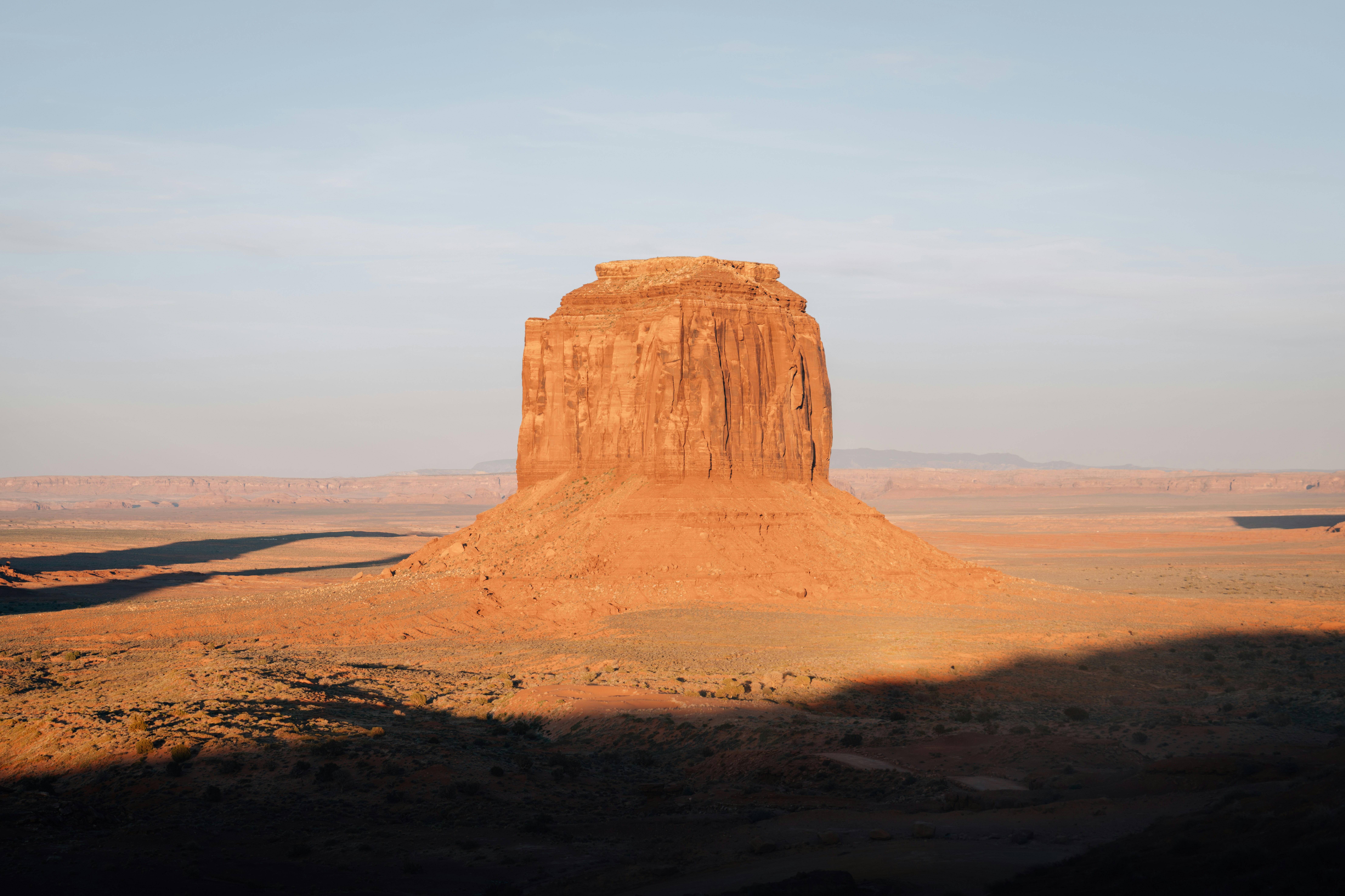 Un solitario butte di arenaria proietta una lunga ombra al tramonto.