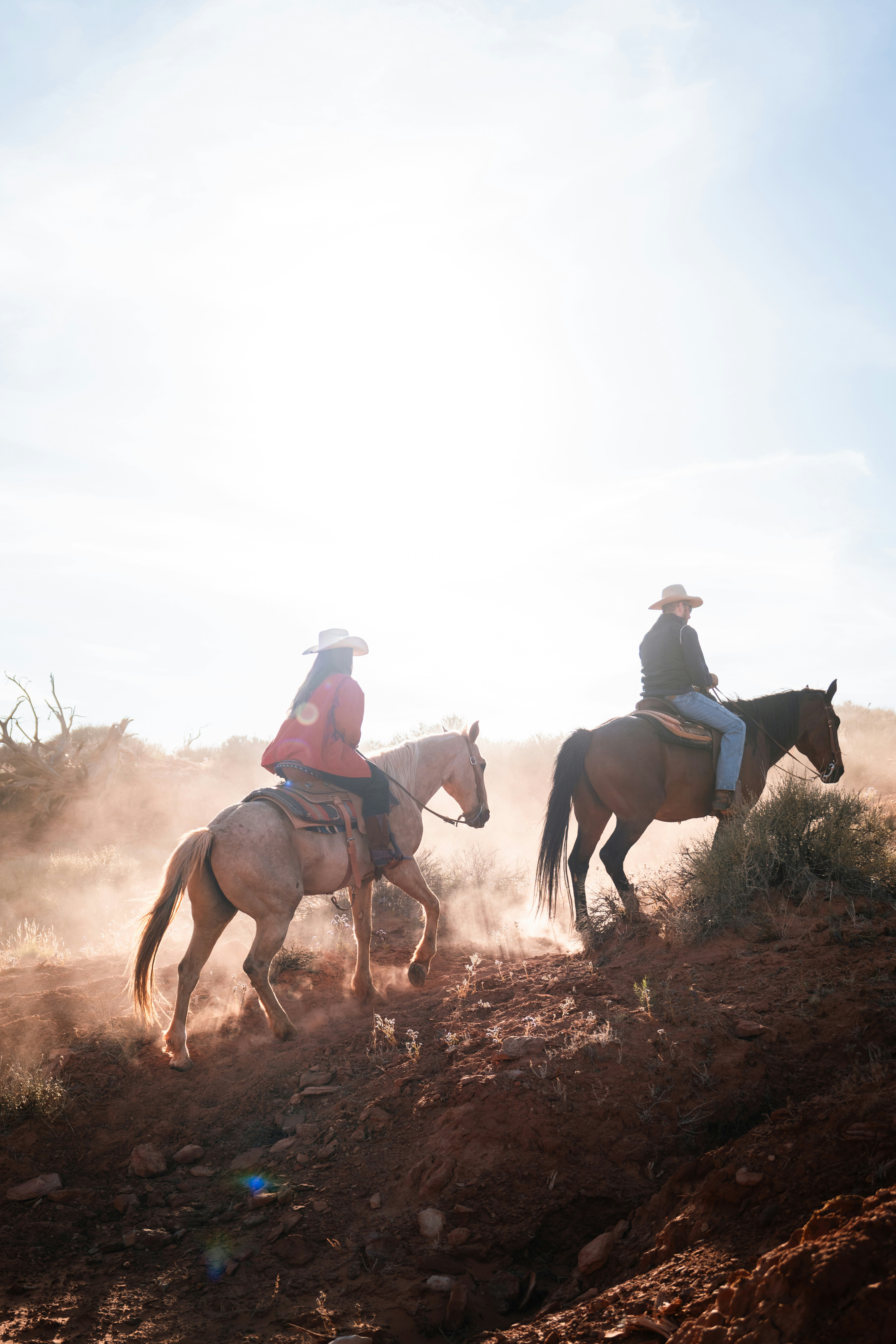 Due persone a cavallo su un sentiero polveroso