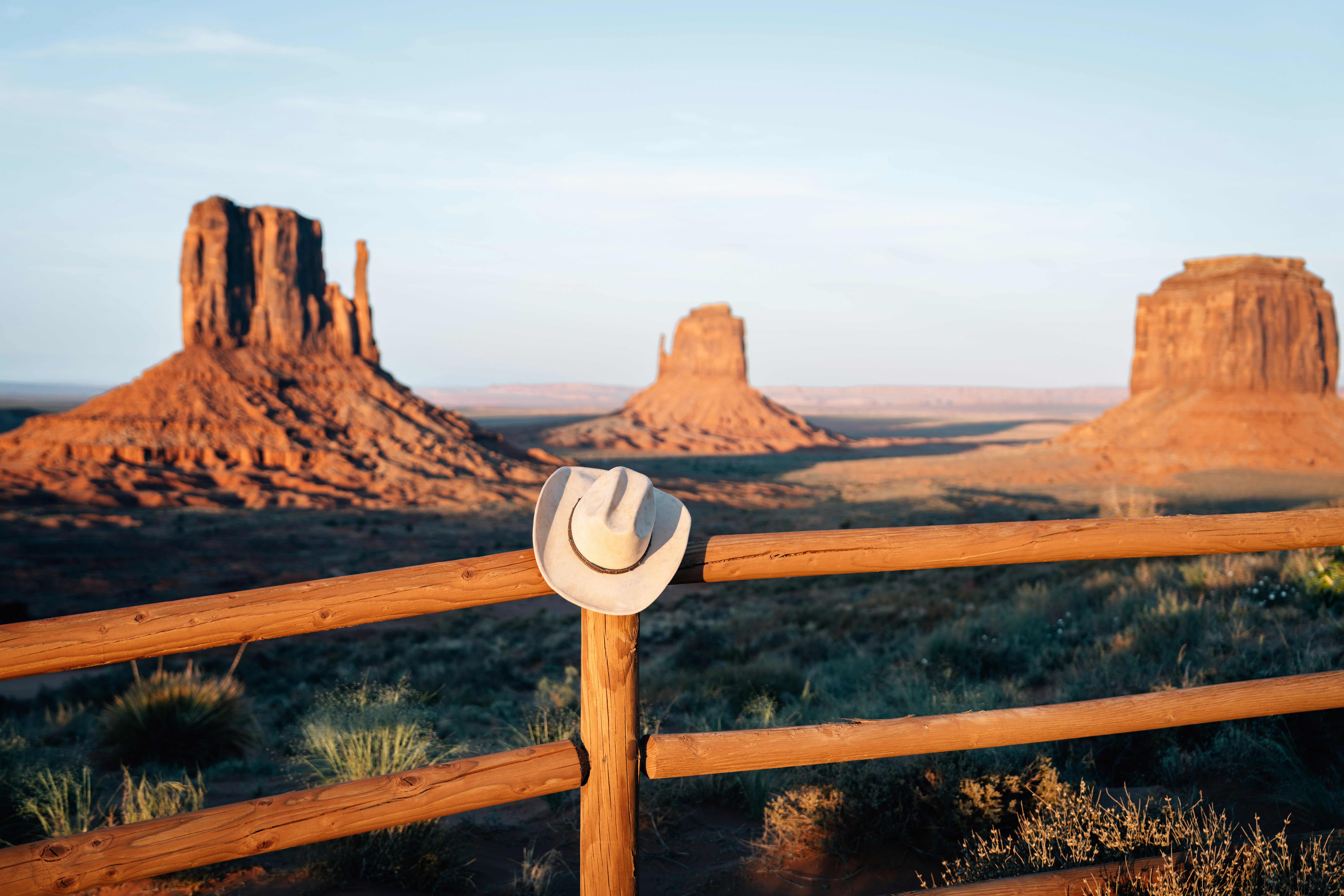 Cowboy hat on wooden fence with monument valley in background.