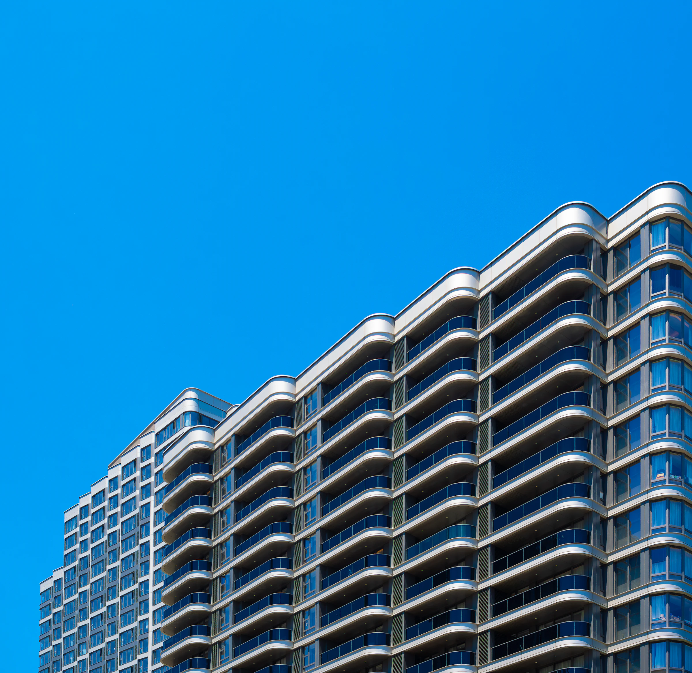 Modern high-rise residential apartment building against a clear blue sky
