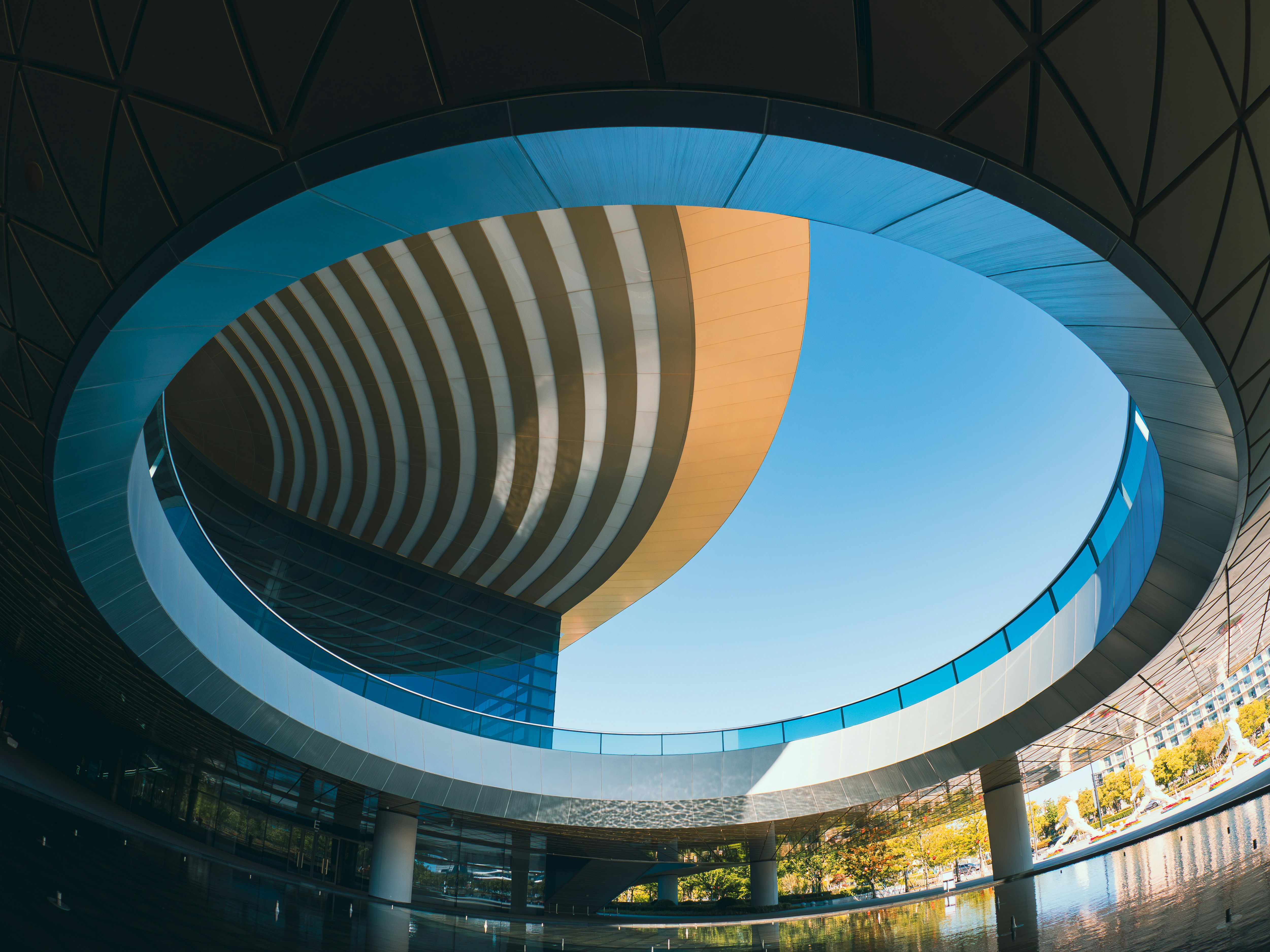 Modern building with circular opening against blue sky
