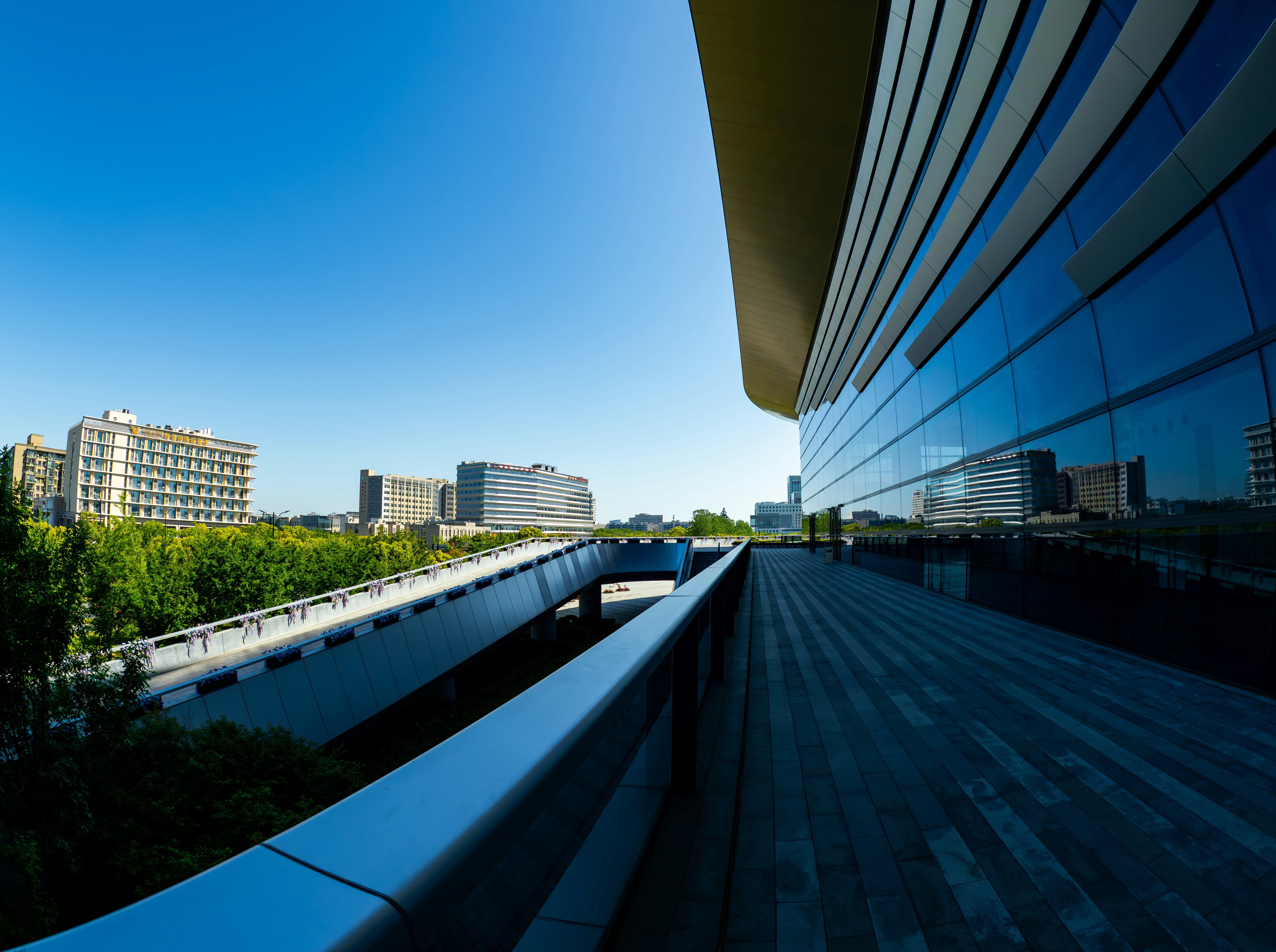 Modern building exterior with glass reflections under blue sky.