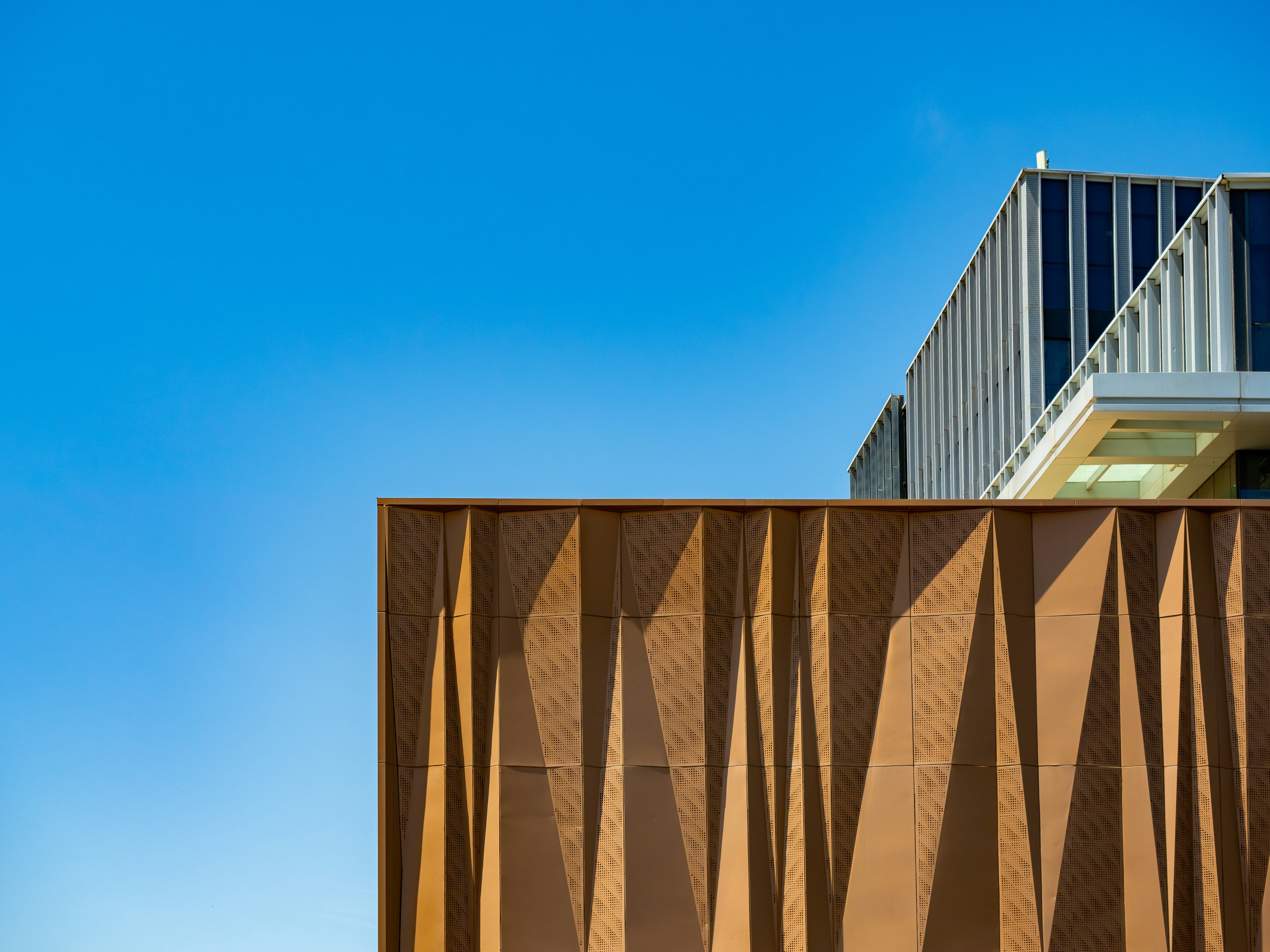 Modern building facade with geometric patterns against blue sky