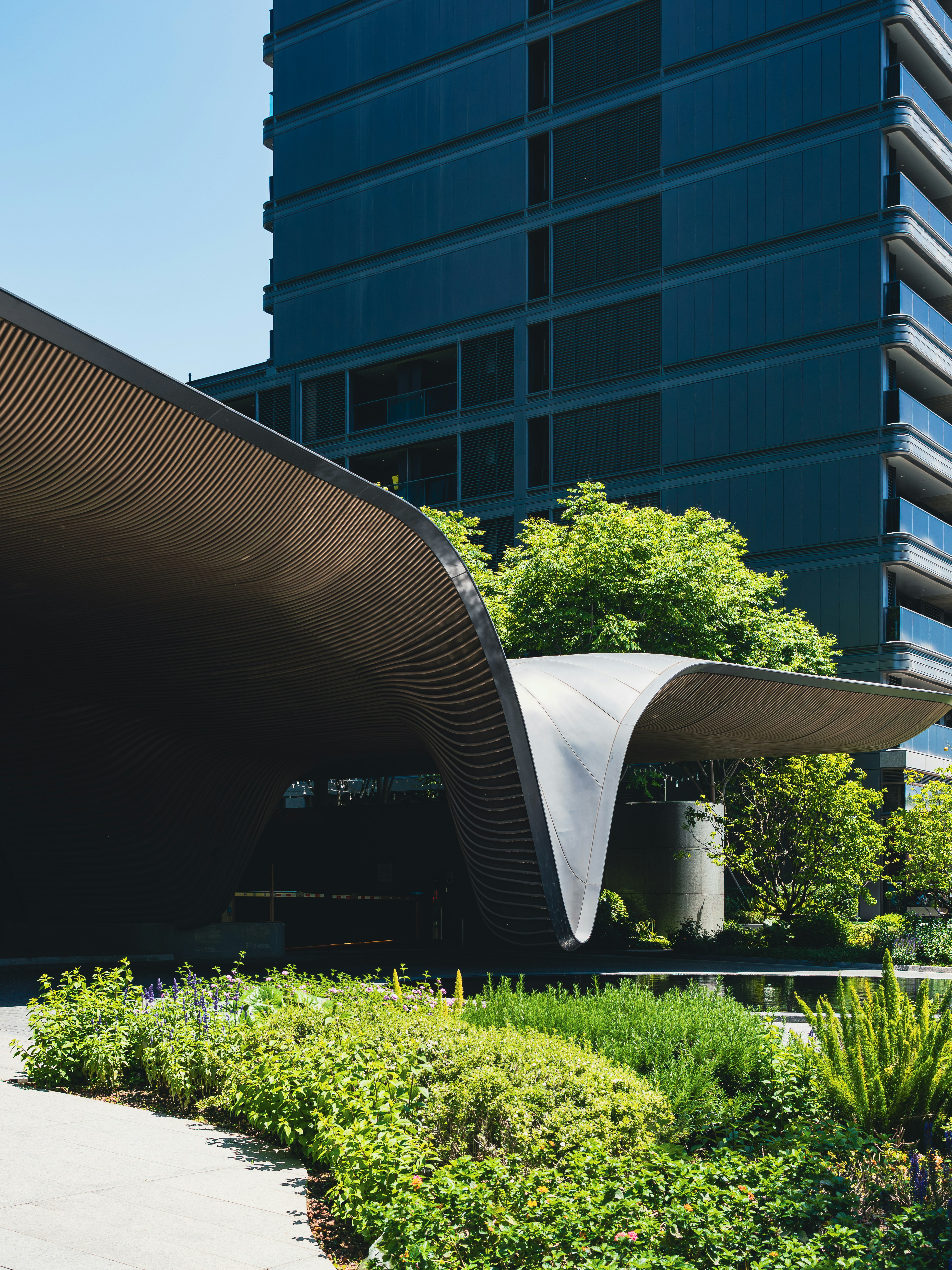 Modern building with curved awning and lush greenery