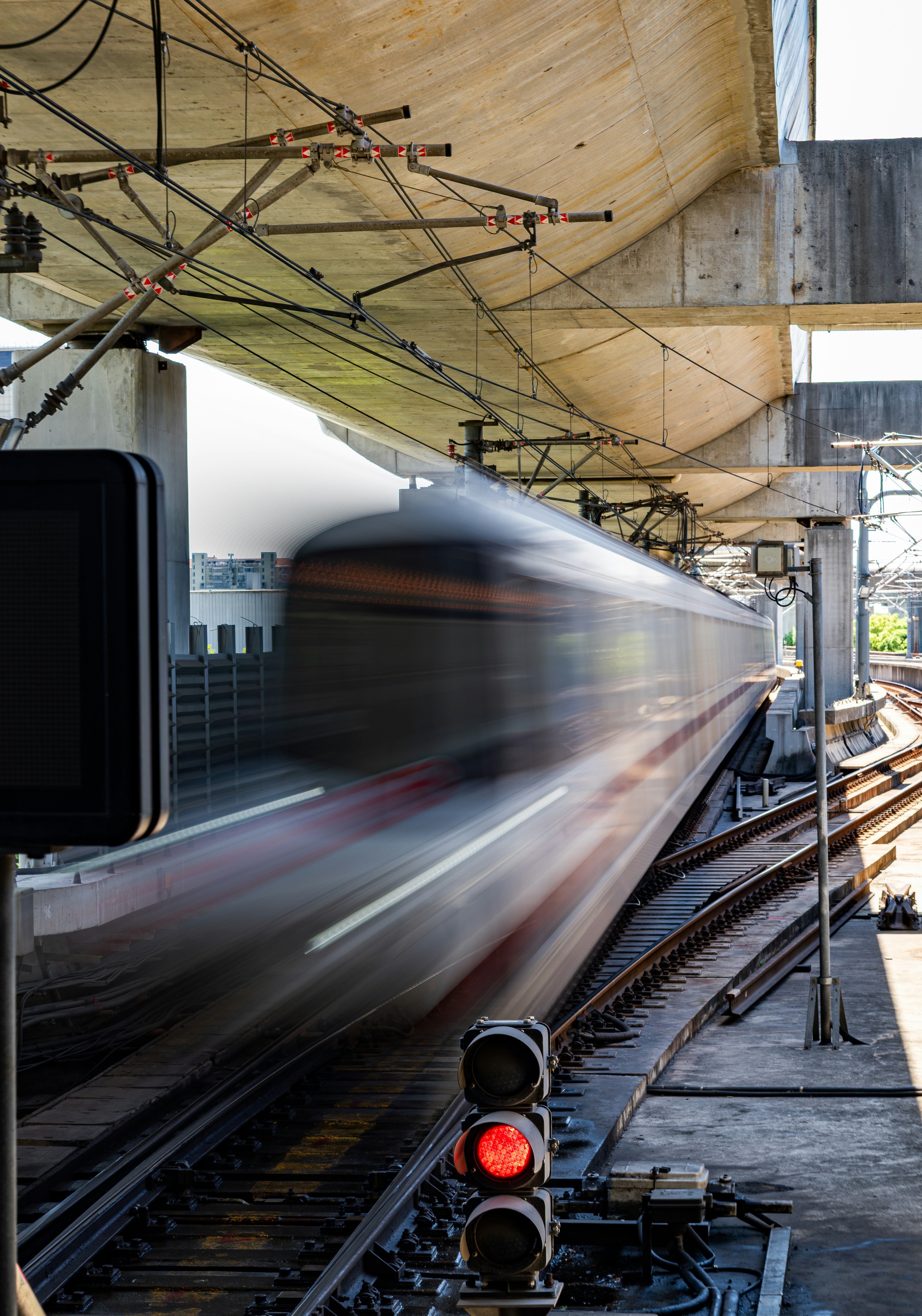 A train speeds by a station with red signal lights.