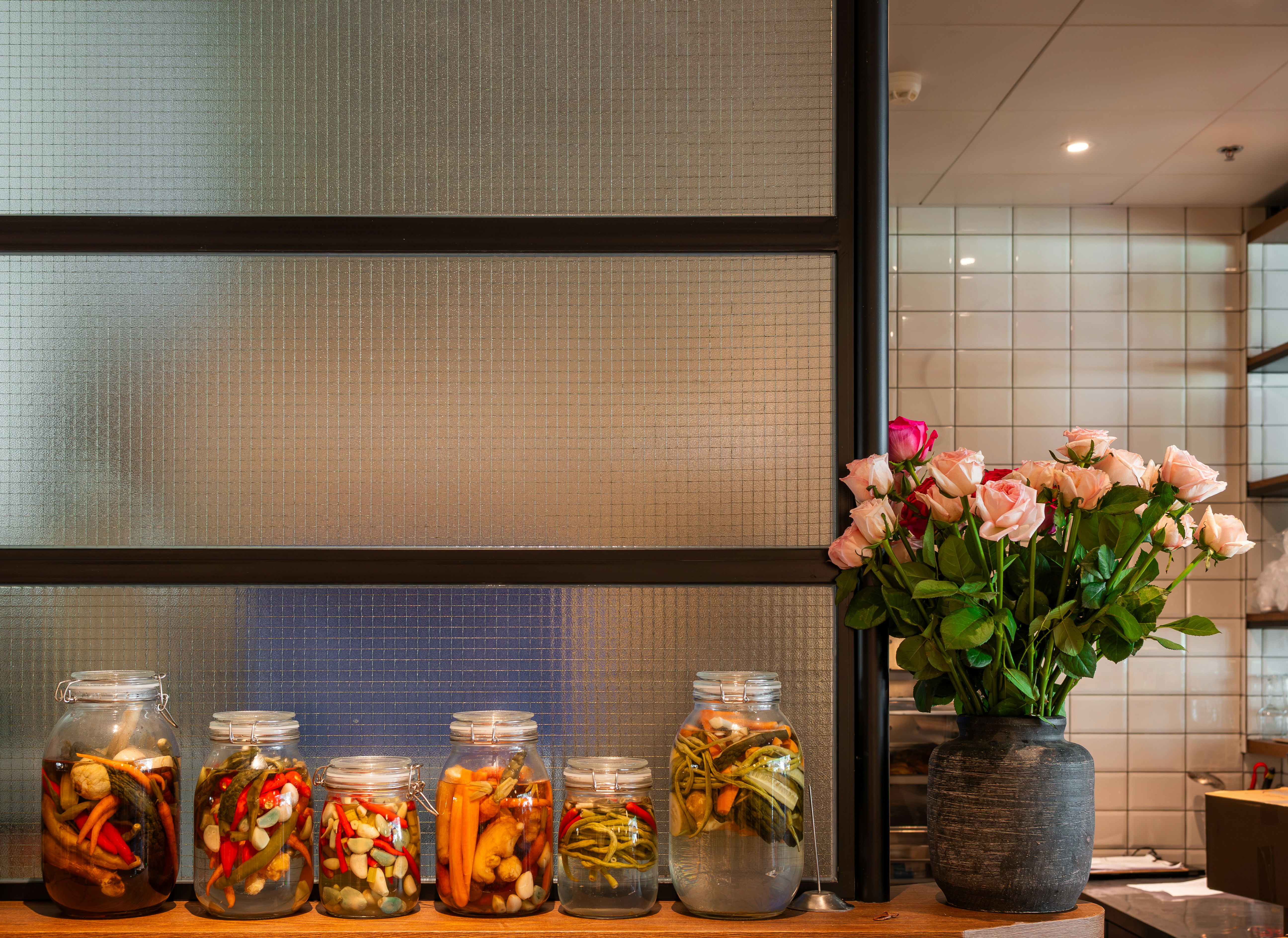 Jars of pickled vegetables and a vase of roses