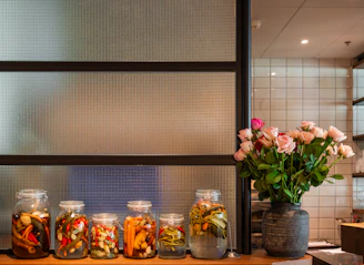 Jars of pickled vegetables and a vase of roses