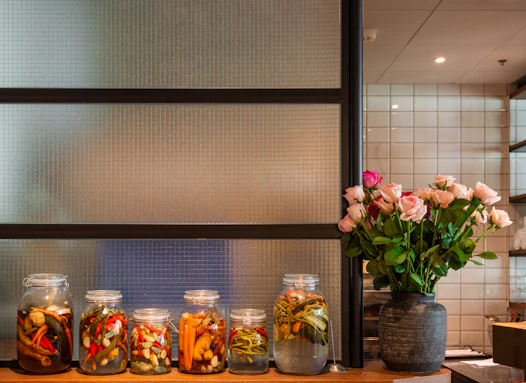 Jars of pickled vegetables and a vase of roses