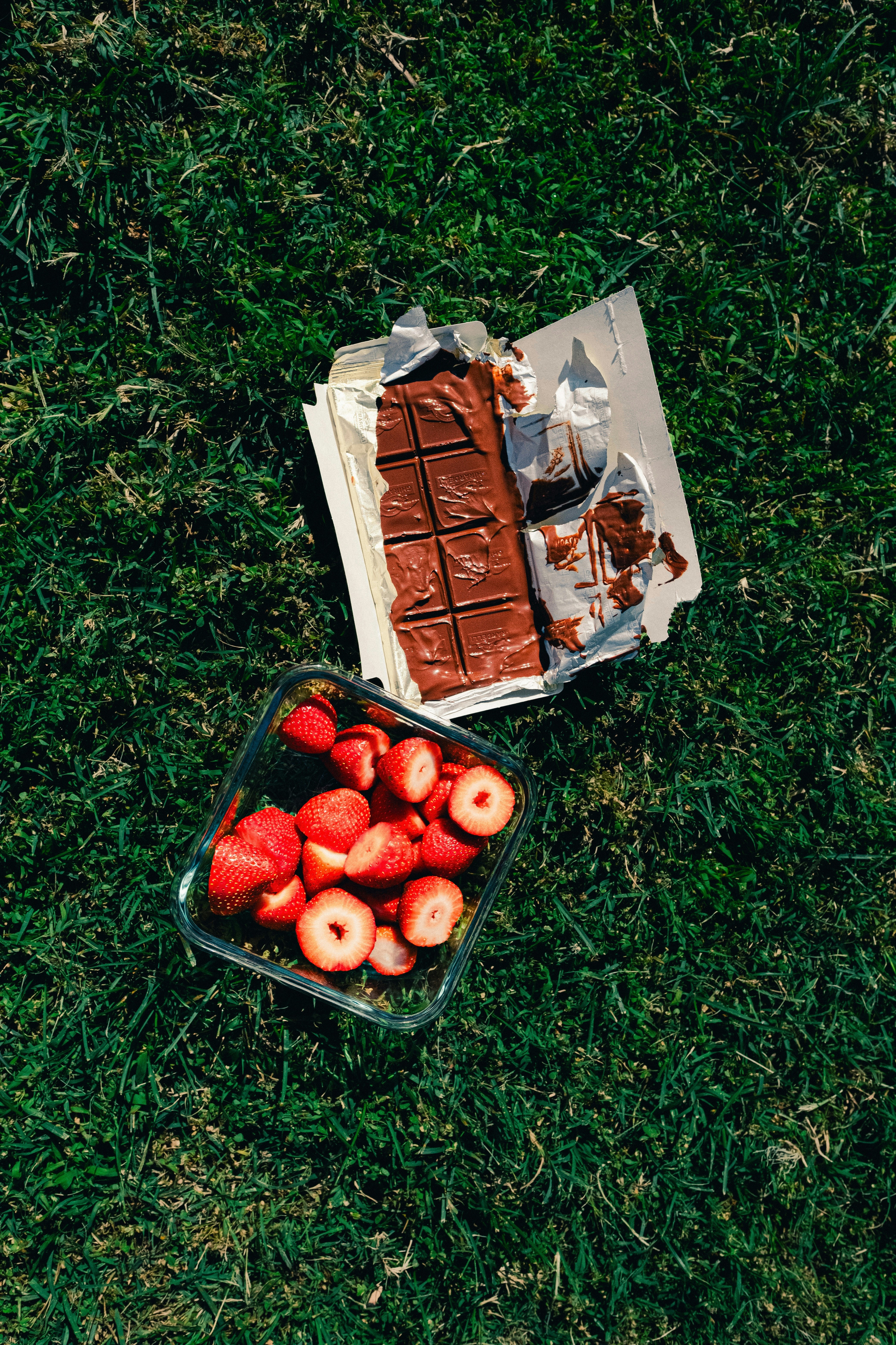 Chocolate bar and strawberries on green grass