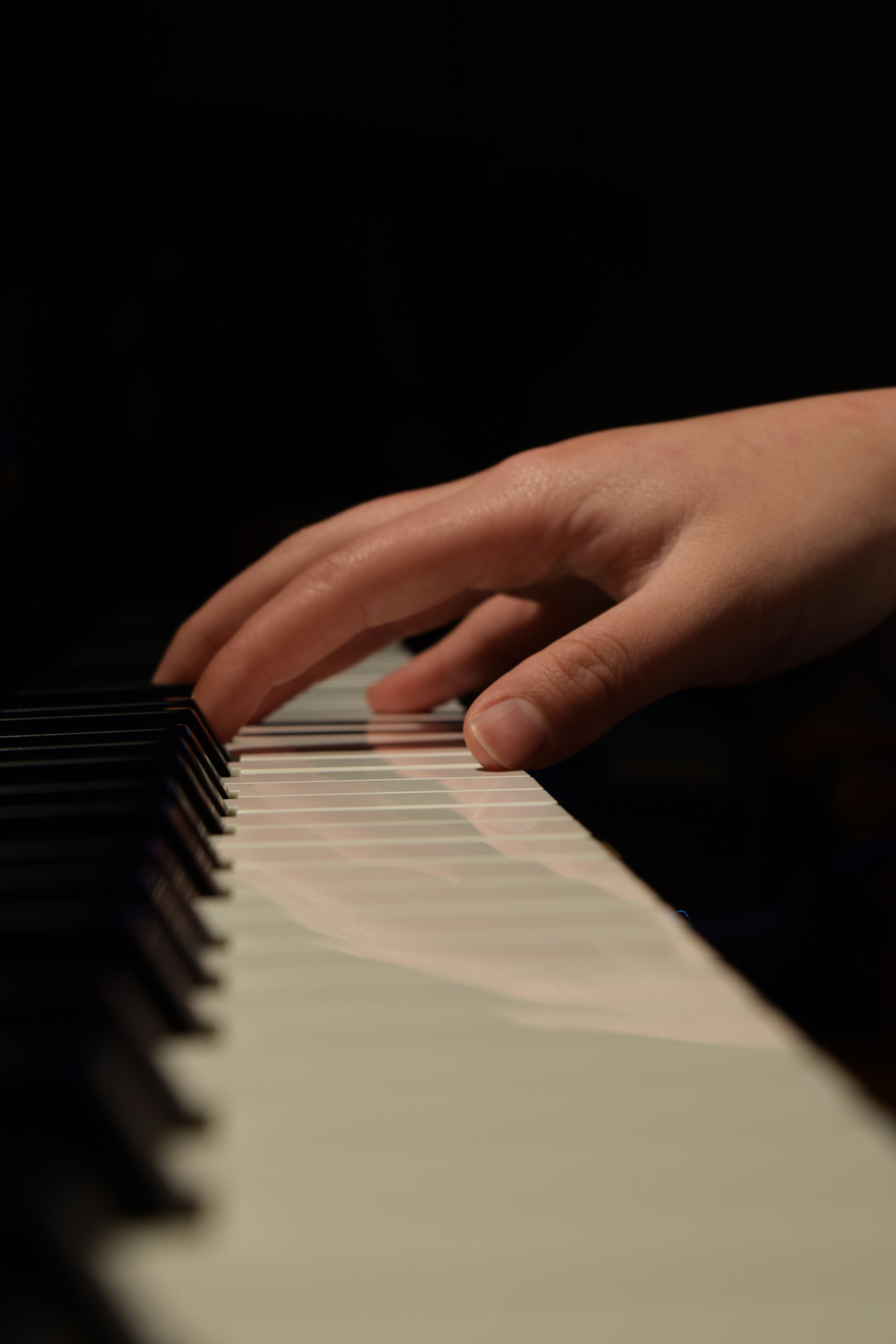 A close-up of a hand playing a piano