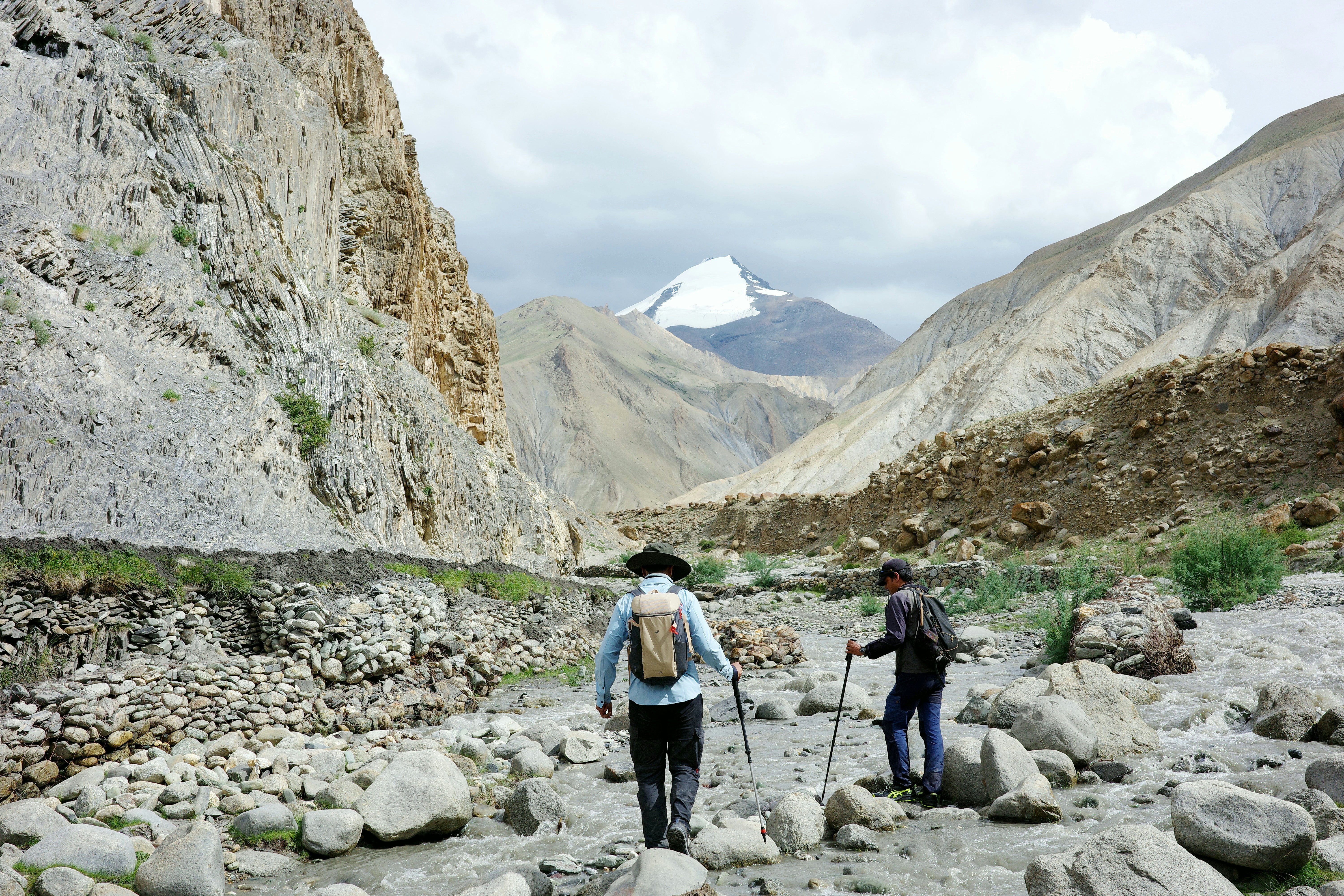 Two hikers walk through a rocky mountain valley.
