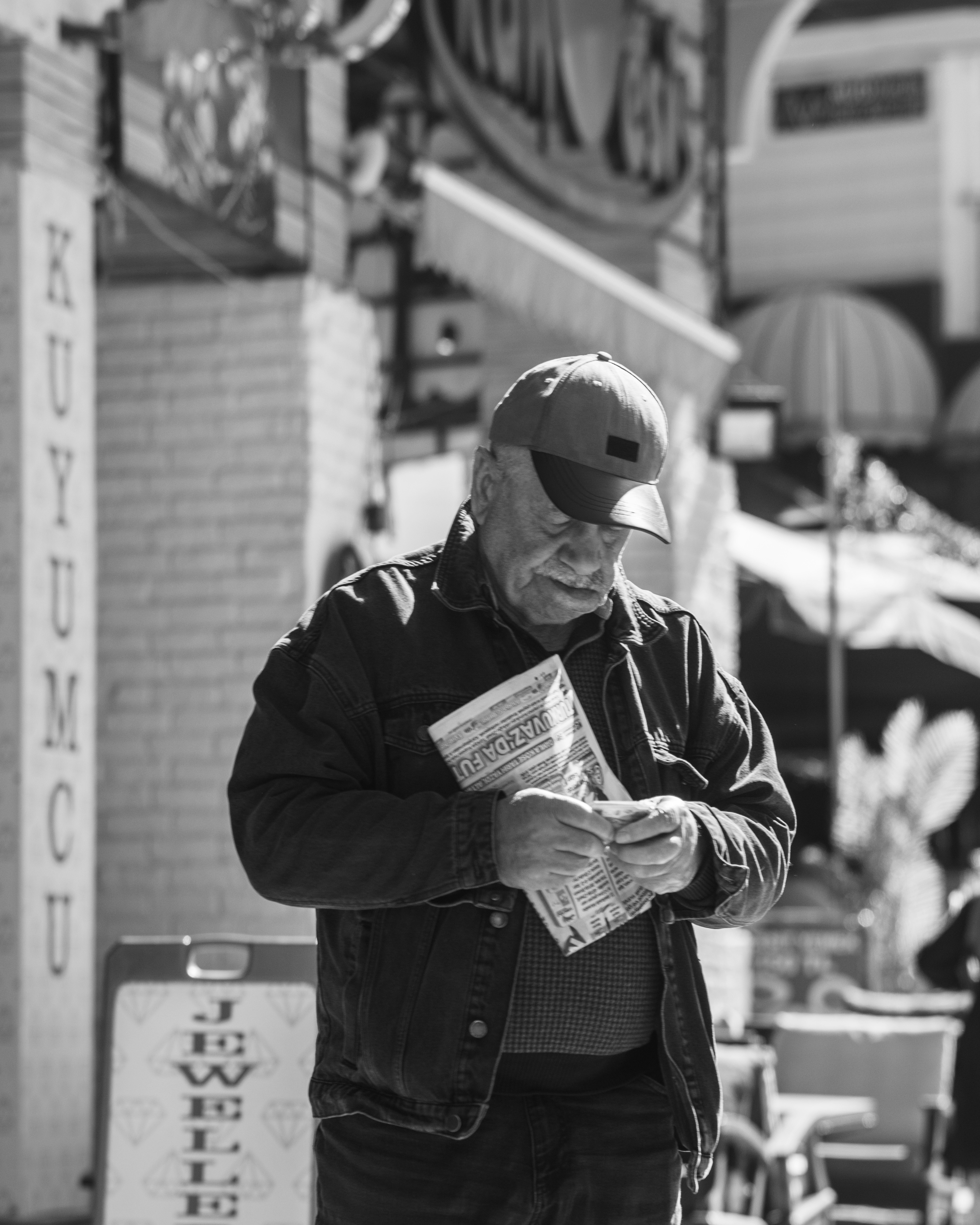 通りで新聞を読んでいる高齢の男性。