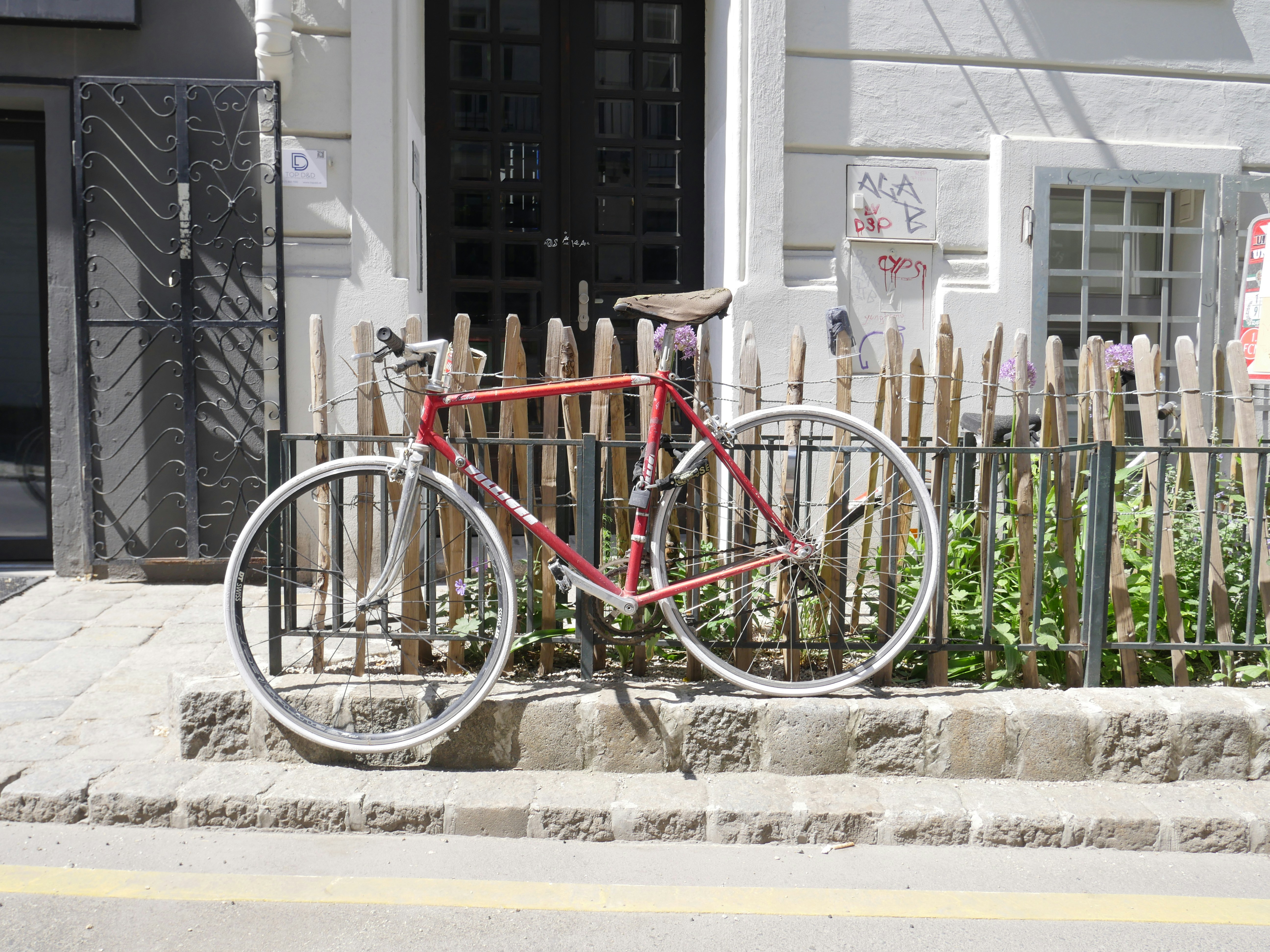 Rotes Fahrrad in der Nähe eines Holzzauns geparkt