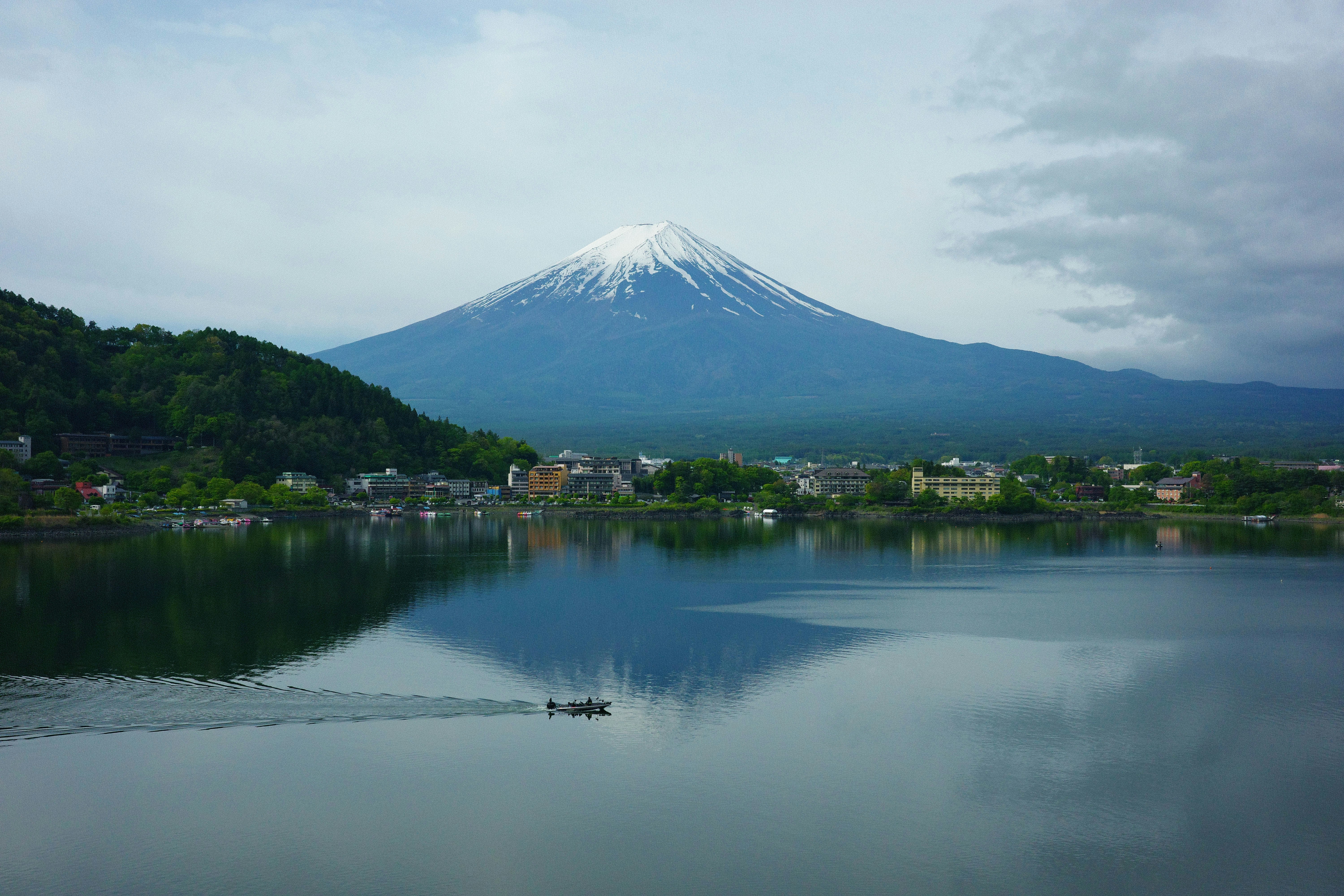 Mount fuji reflected in a calm lake with a boat.